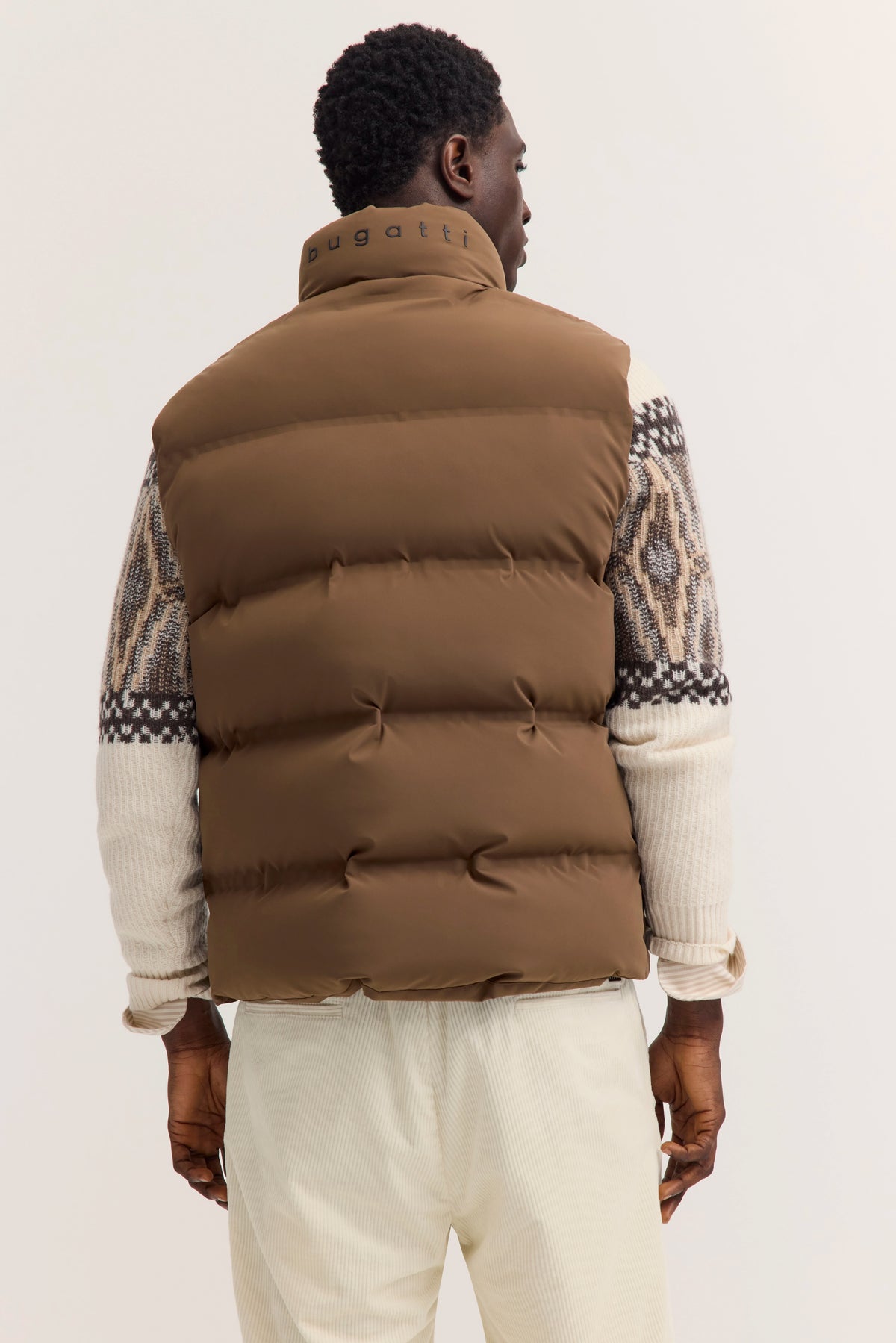Braune bugatti Weste, gemusterter Pullover in Beige und Weiß, Model von hinten betrachtet.
