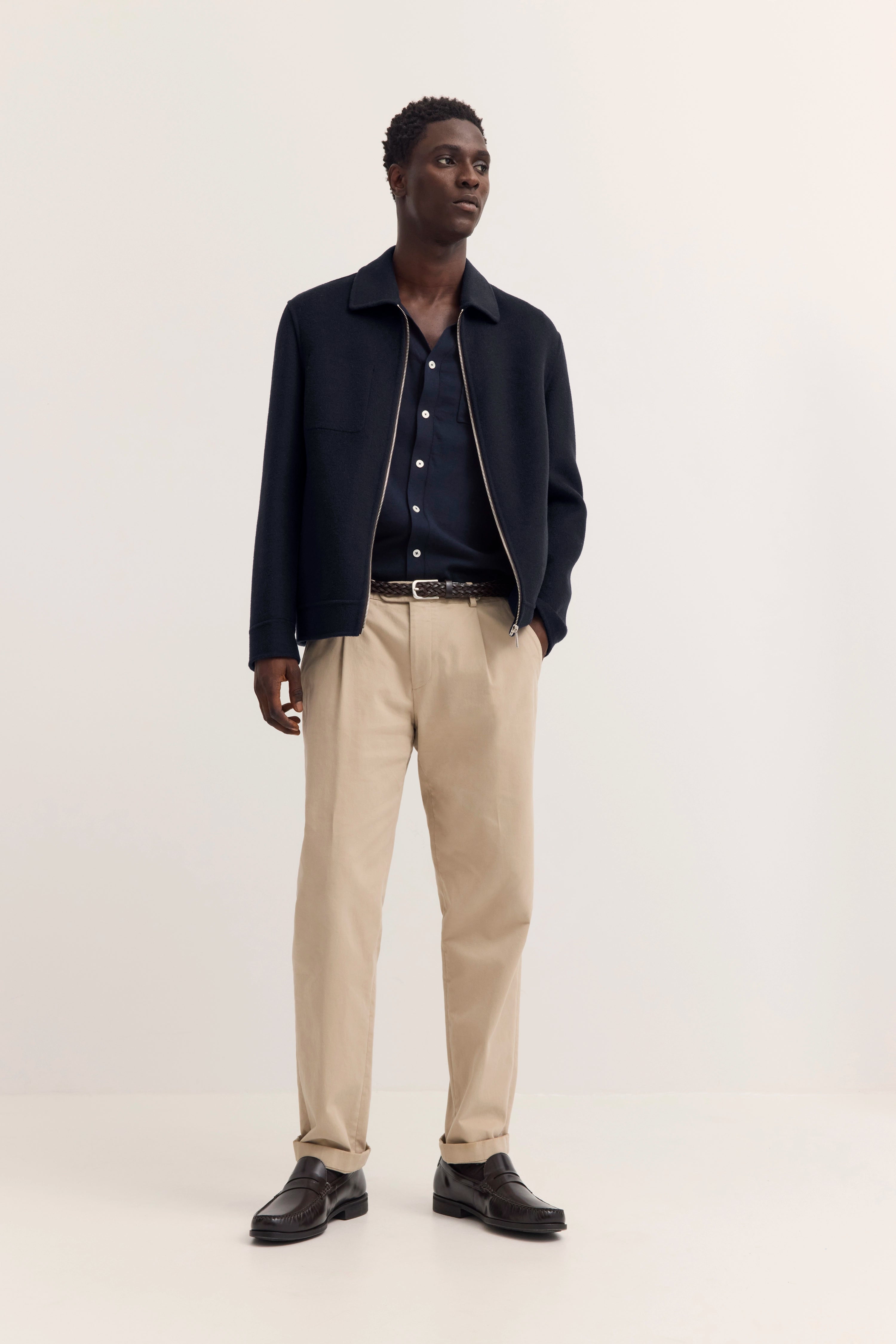Bugatti Modelbild: Dunkelblaue Jacke mit Reißverschluss über dunkelblauem Hemd, entspannte Haltung.