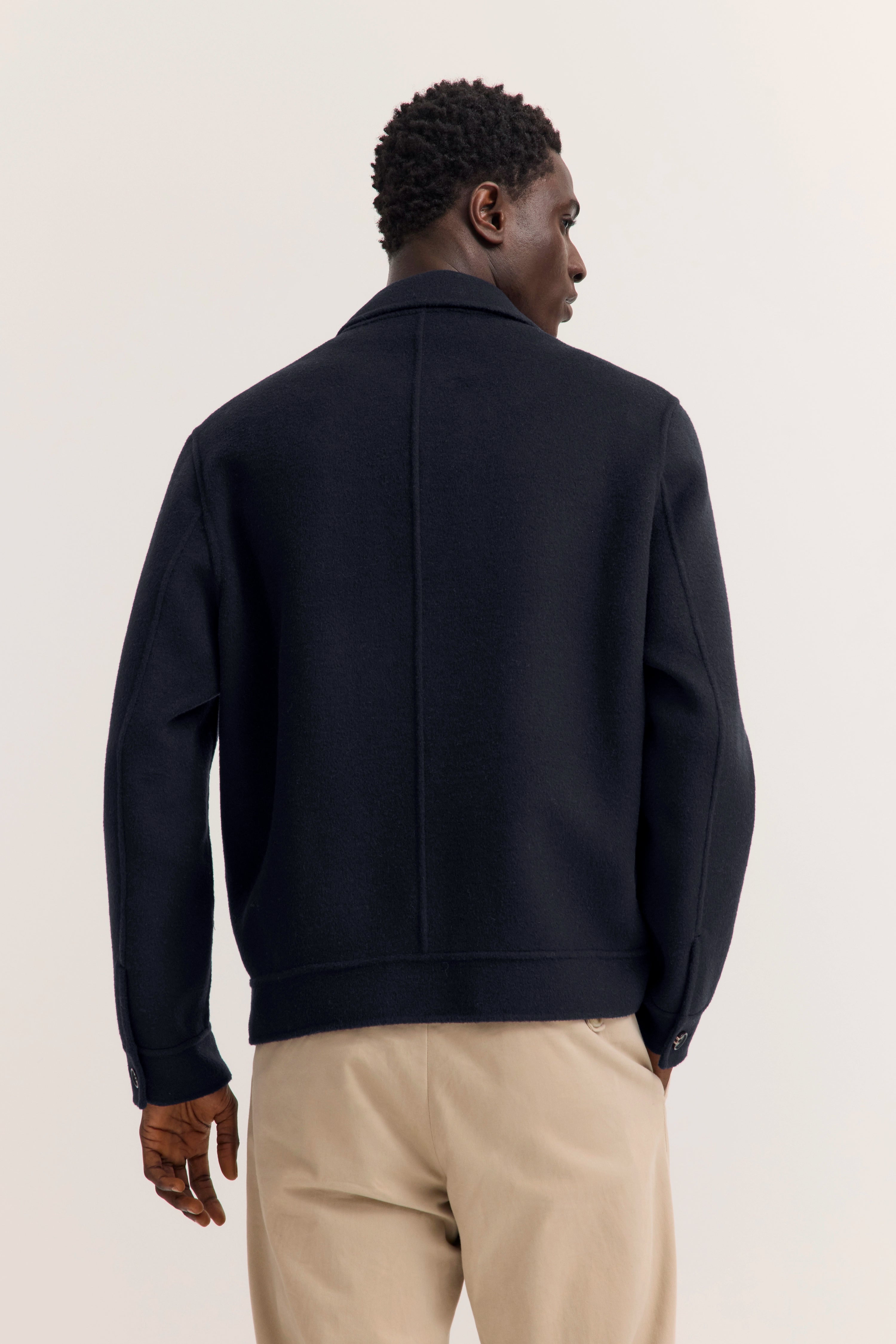  Model steht frontal mit Händen in den Taschen.