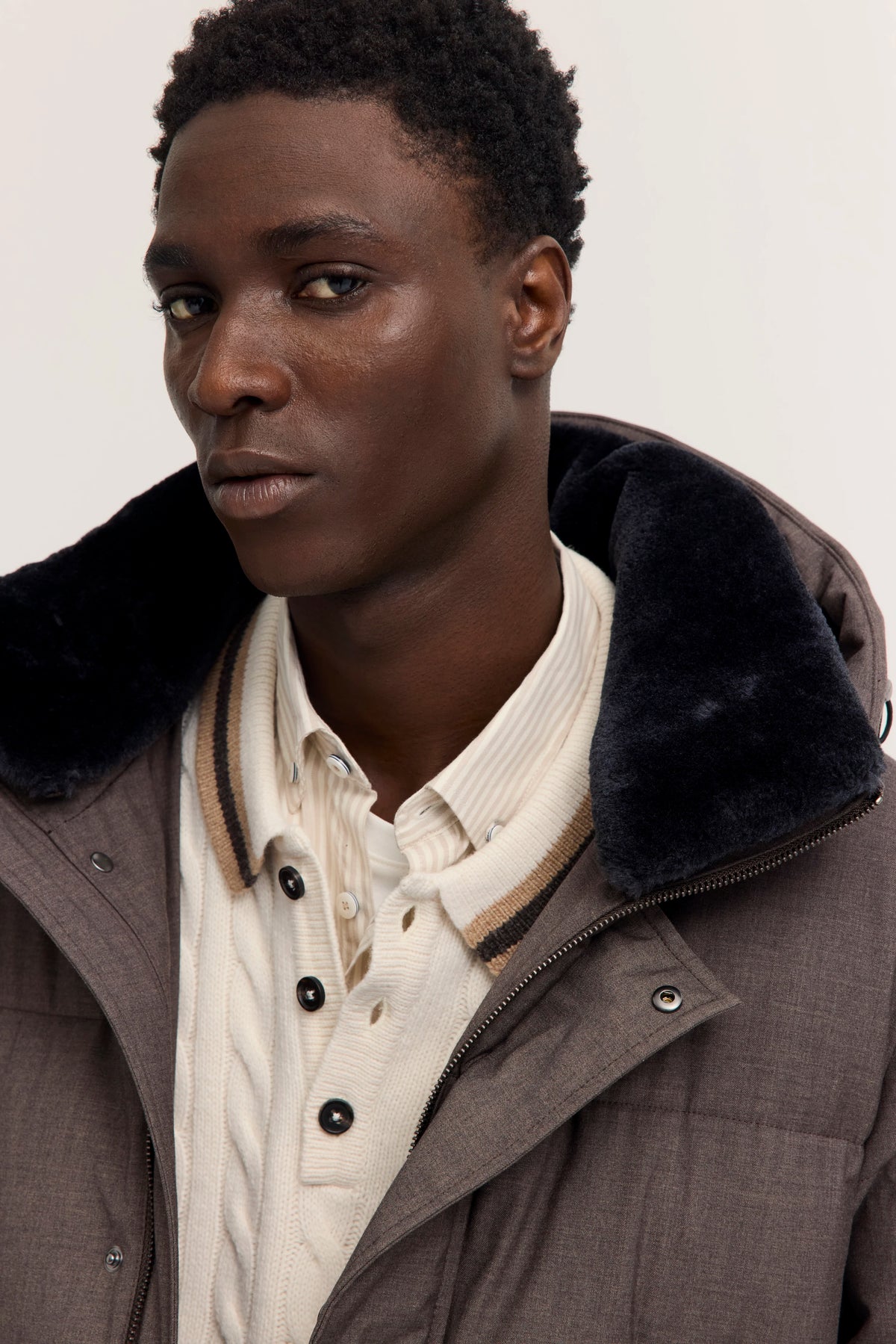 Bugatti Modelbild: Mann in brauner Jacke mit flauschigem Kragen, cremefarbenem Pullover und Hemd, Halbprofil.