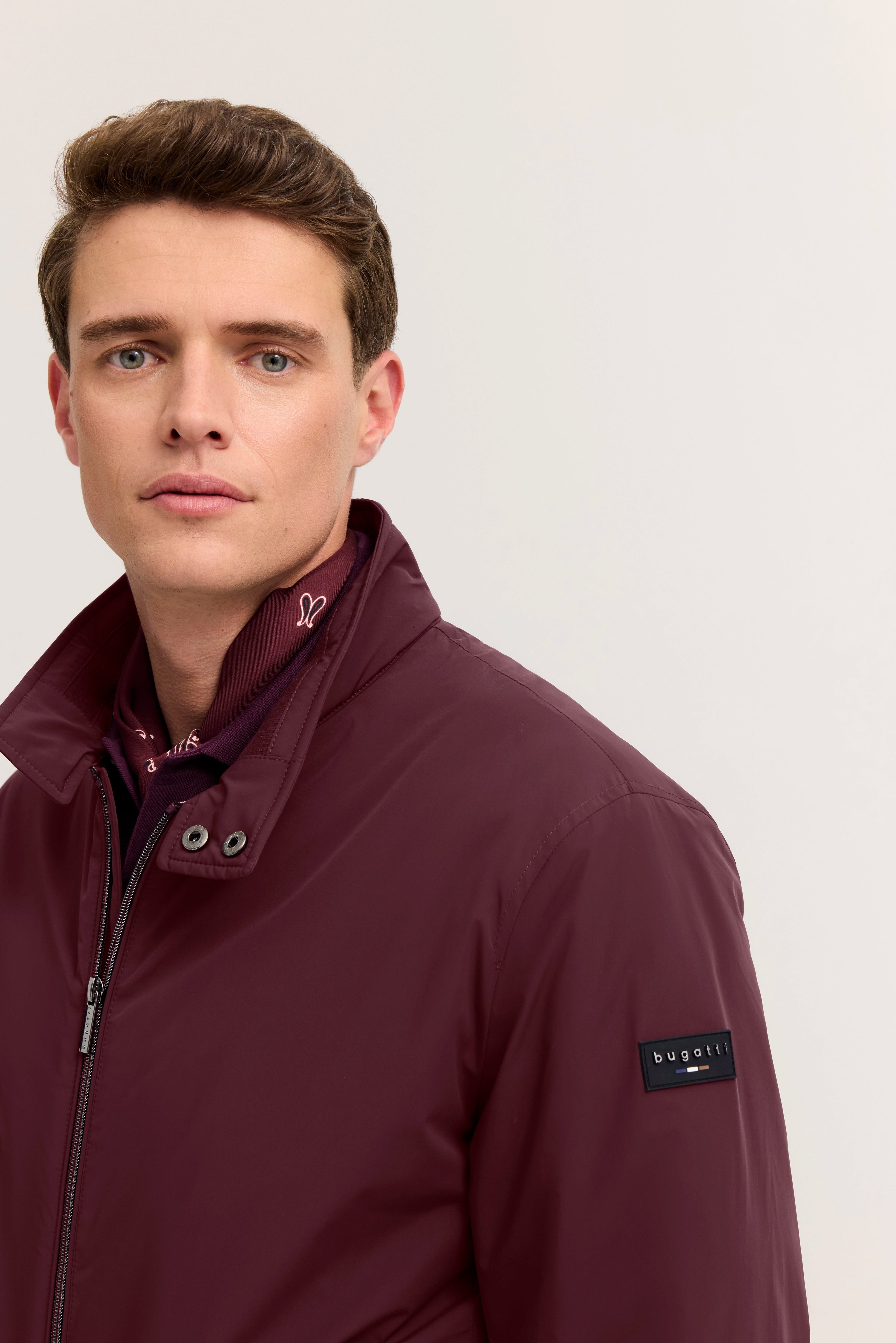 Modelbild, Mann in bordeauxfarbener bugatti Jacke, legeres Posing, stilvolle Eleganz.