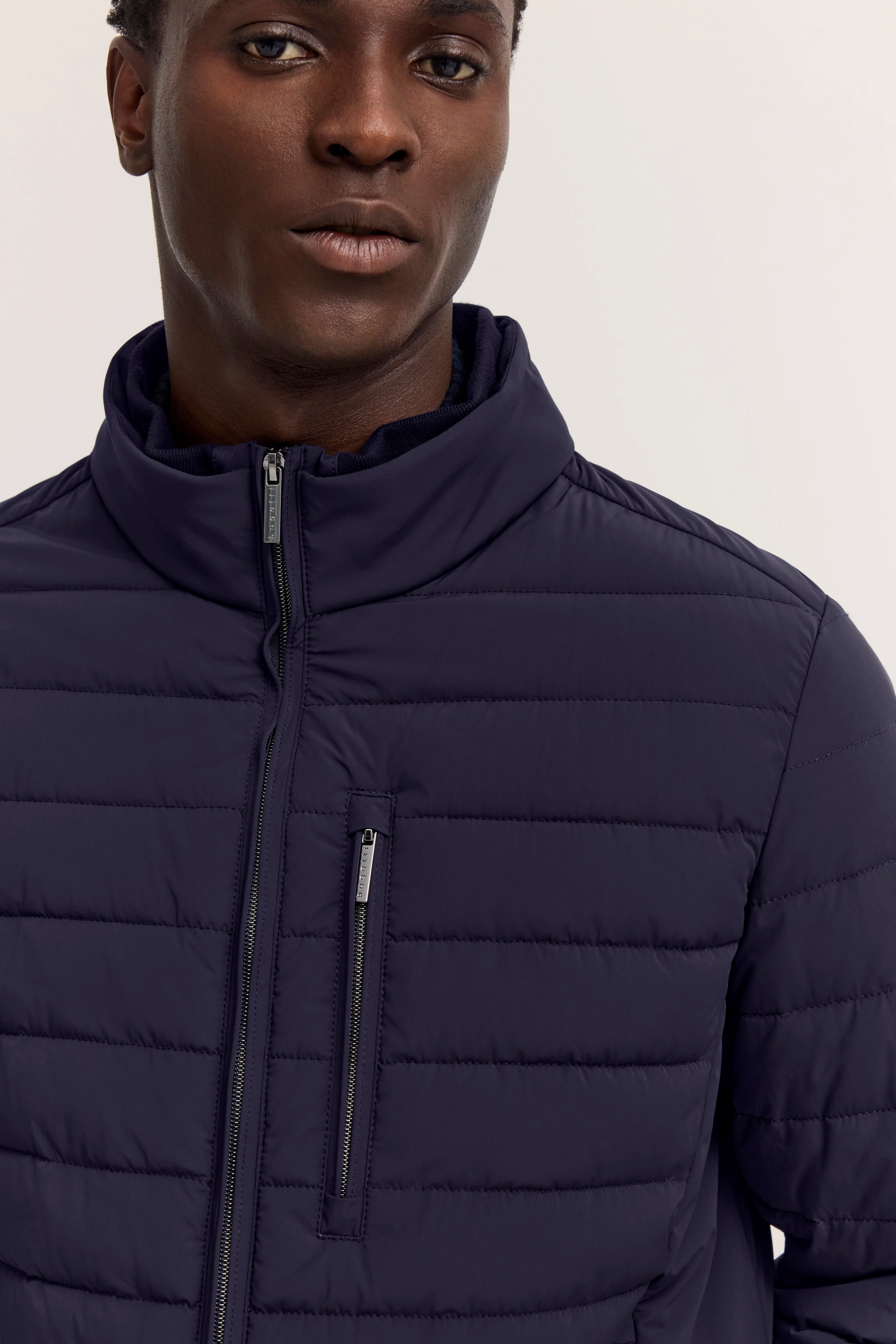 Dunkelblaue Steppjacke von bugatti, Modelbild von hinten, entspannte Pose.