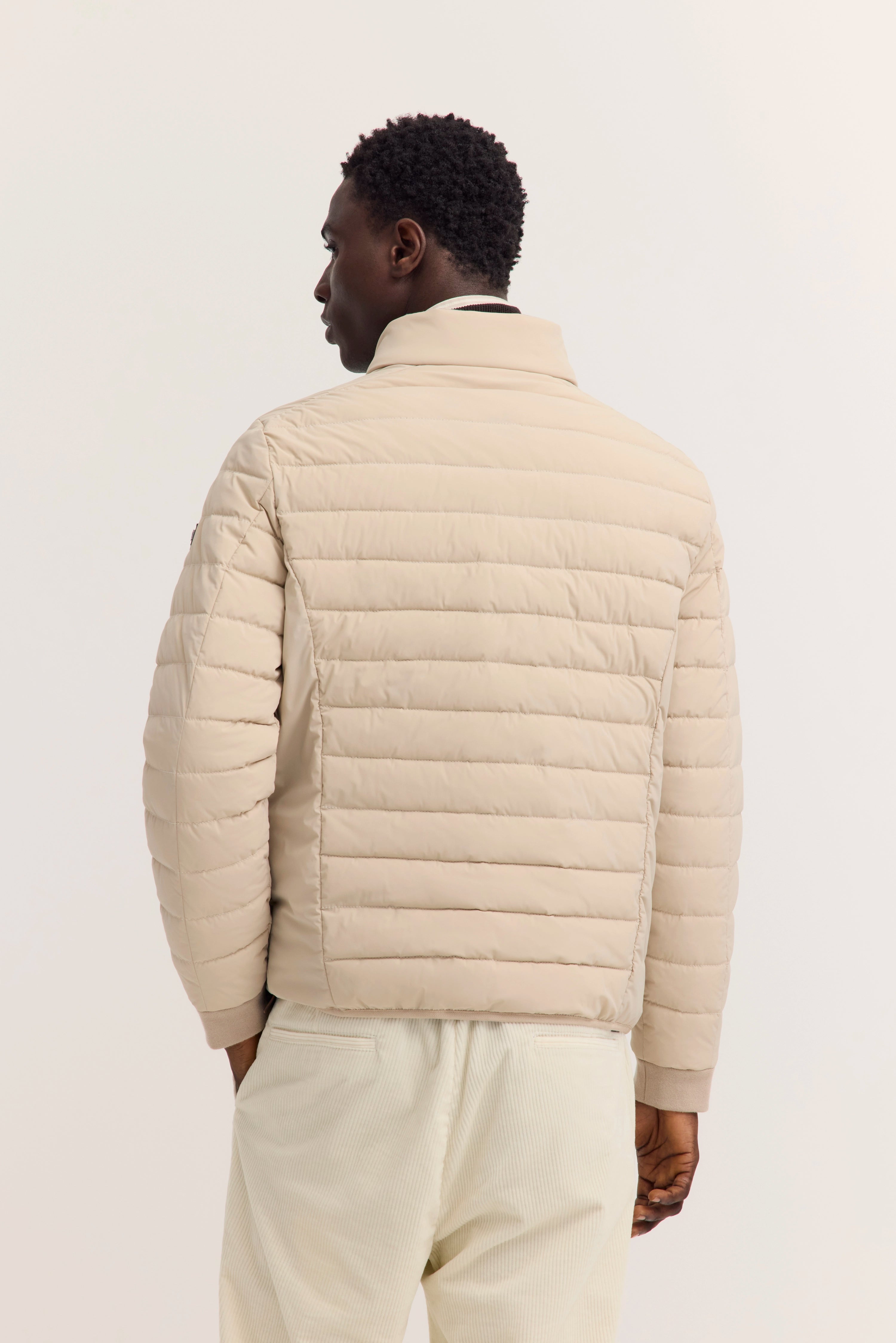 Beigefarbene Steppjacke von bugatti, Modelbild von hinten, lässige Pose.