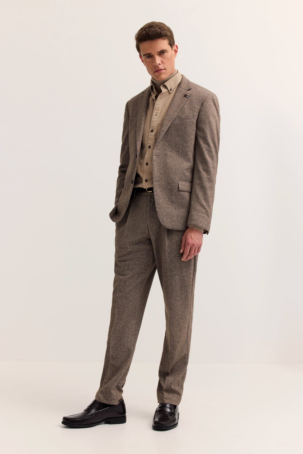 Eleganter bugatti Anzug in Braun, Hemd in Beige, Model posiert leger mit geneigtem Kopf.