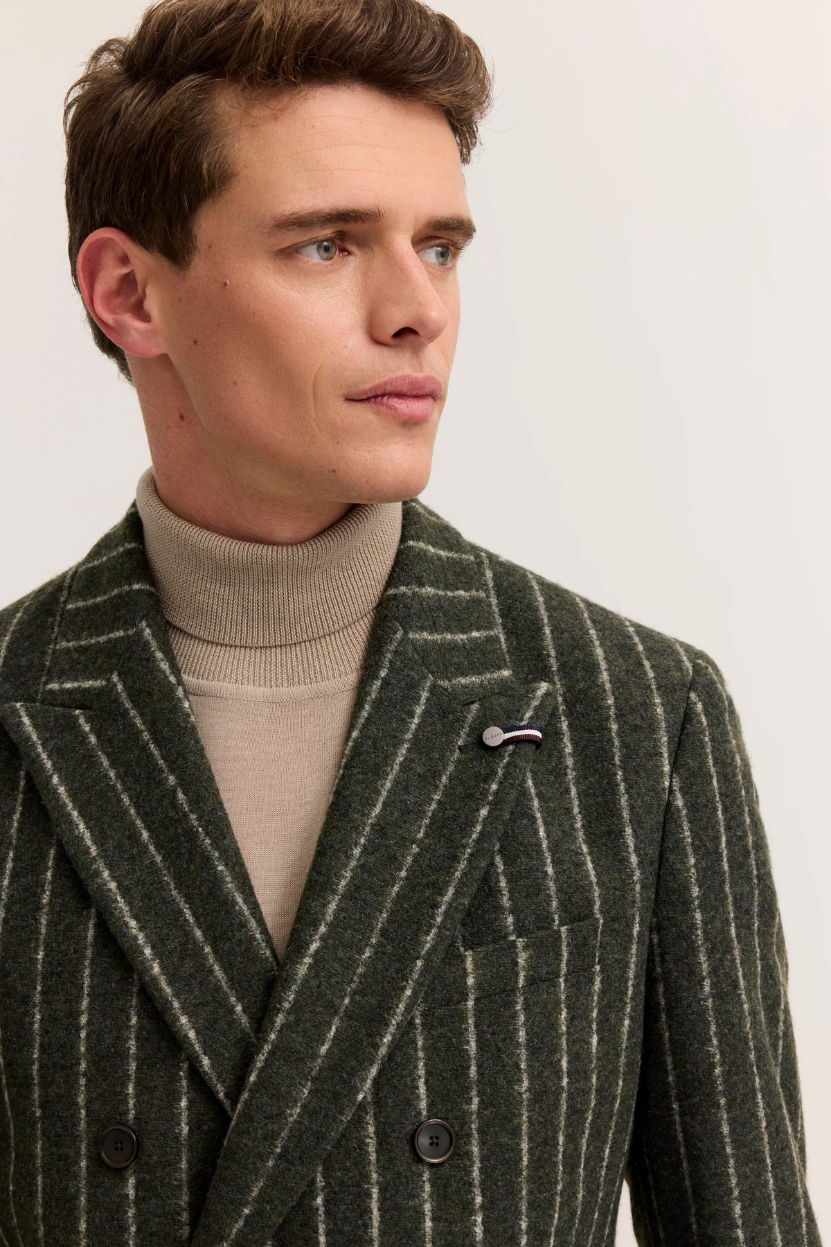 Grüner gestreifter Blazer von bugatti, beige Rollkragen, Model seitlich blickend.