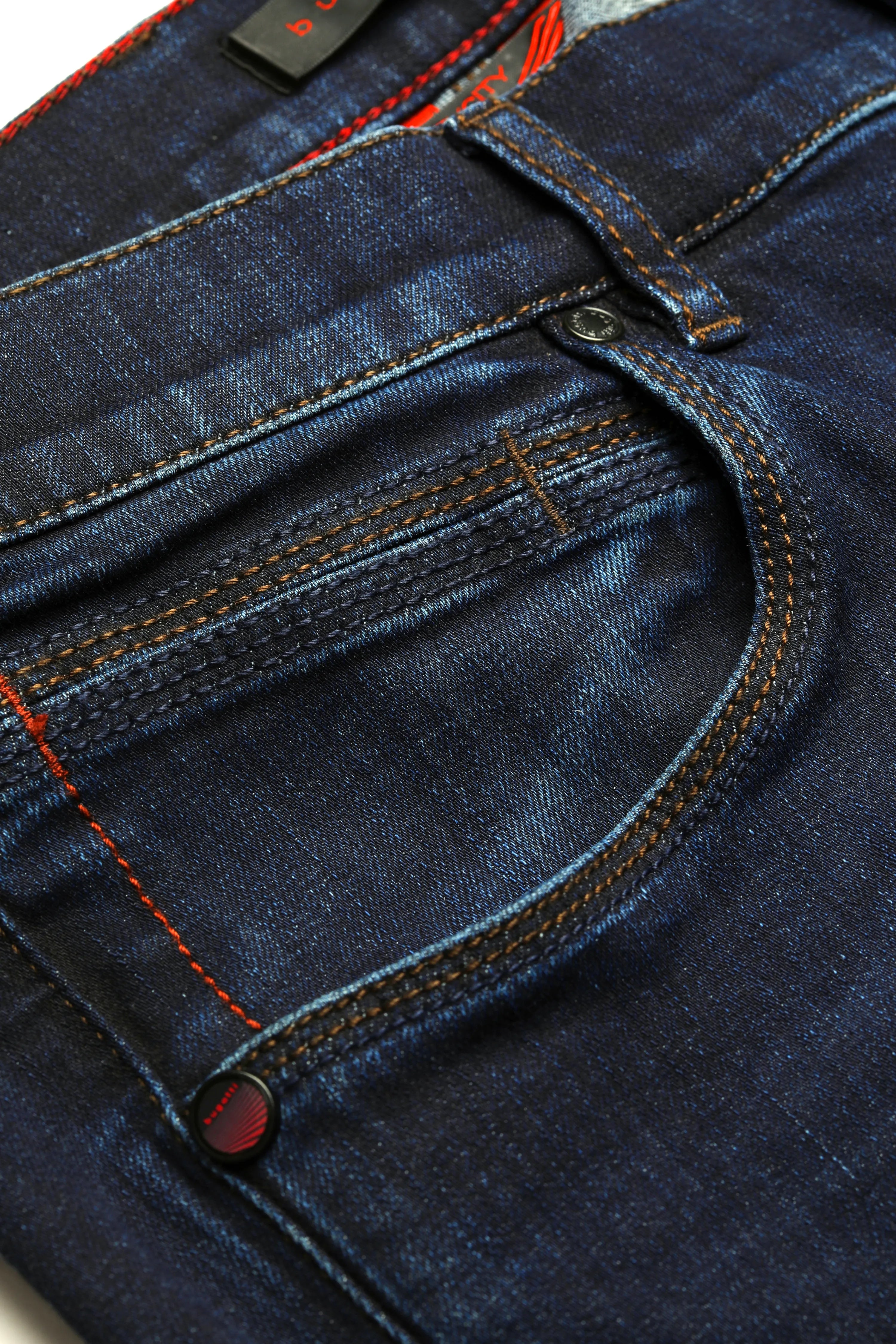 Dunkelblaue bugatti Jeans mit roten Nähten, Detailansicht, hochwertige Materialien.