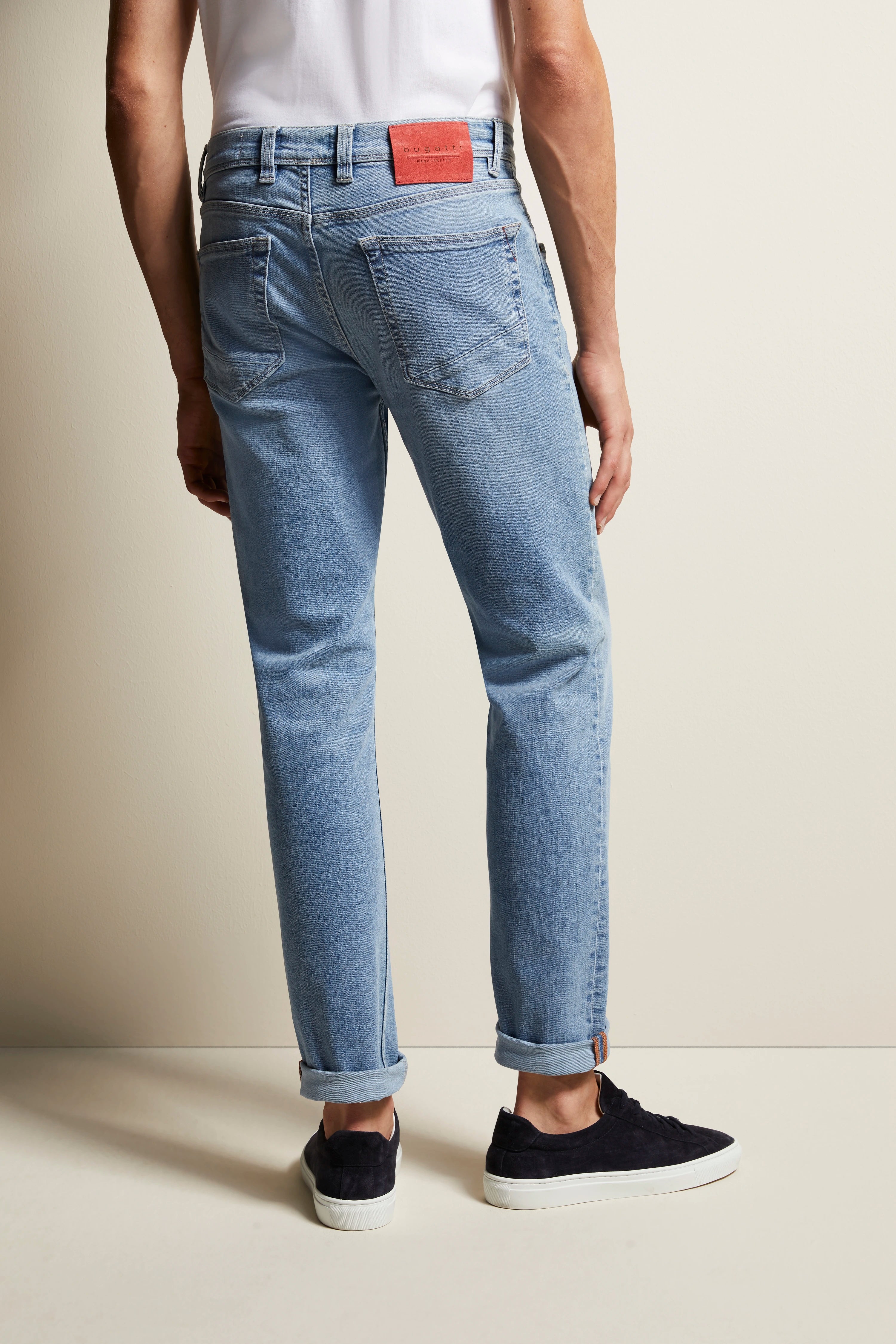 Herrenjeans in hellblauem Denim, legeres Modelbild von hinten, kombiniert mit weißen Sneakern.