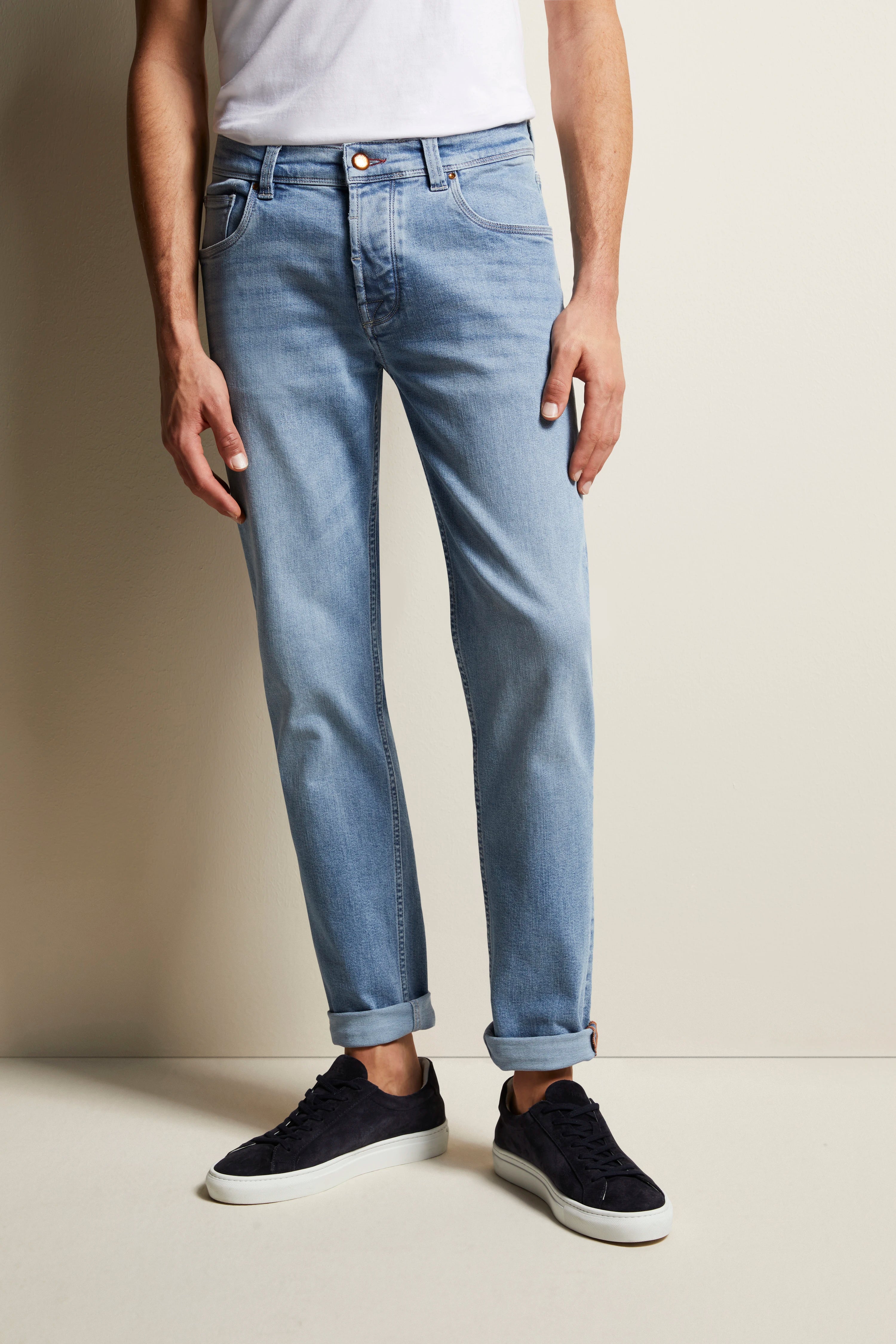 Hellblaue Jeans und schwarze Sneaker, legeres Modelbild, stehende Pose.