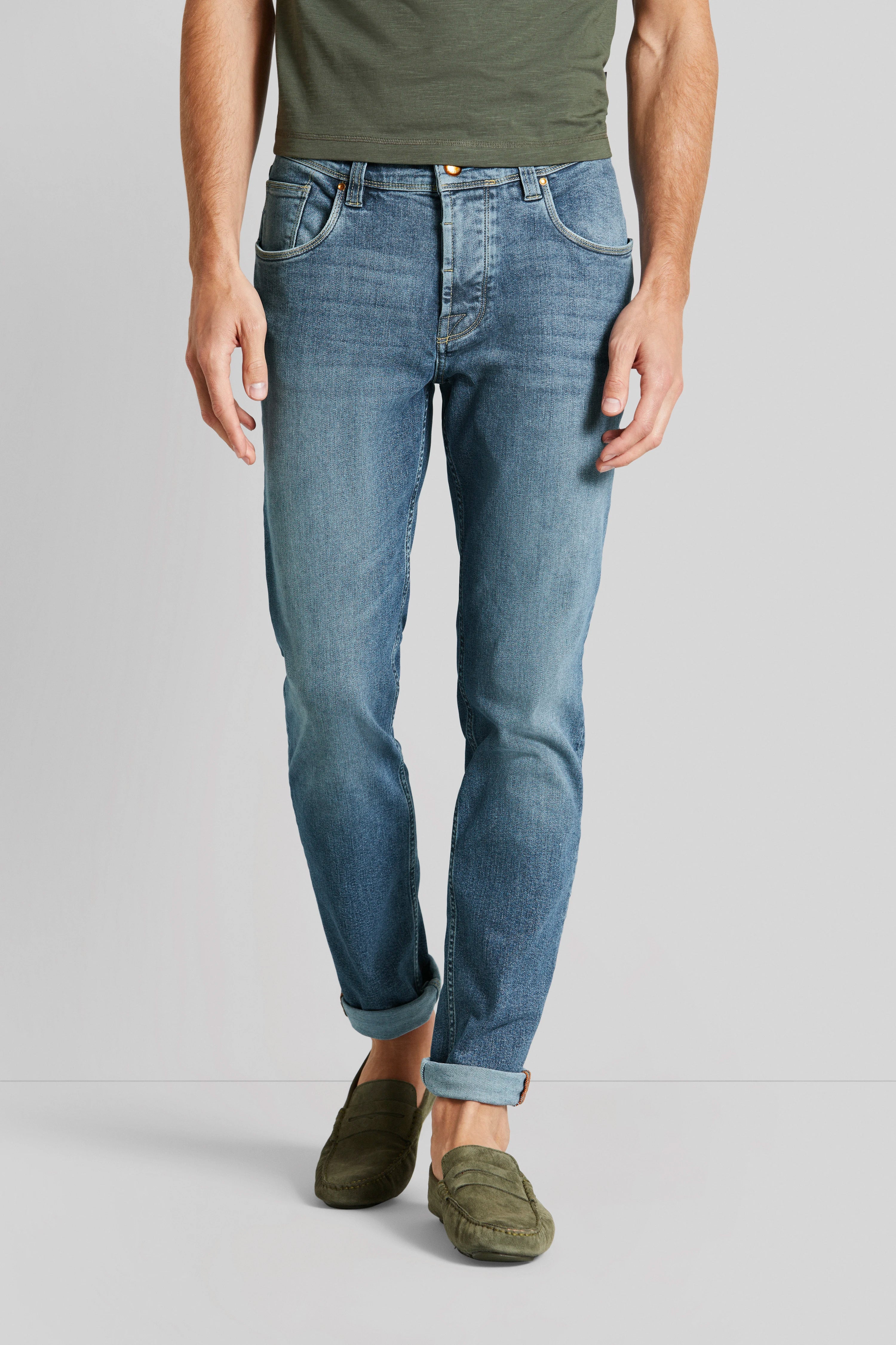 Jeans in Blau mit grünen Loafern, legeres Modelbild, entspannte Pose.