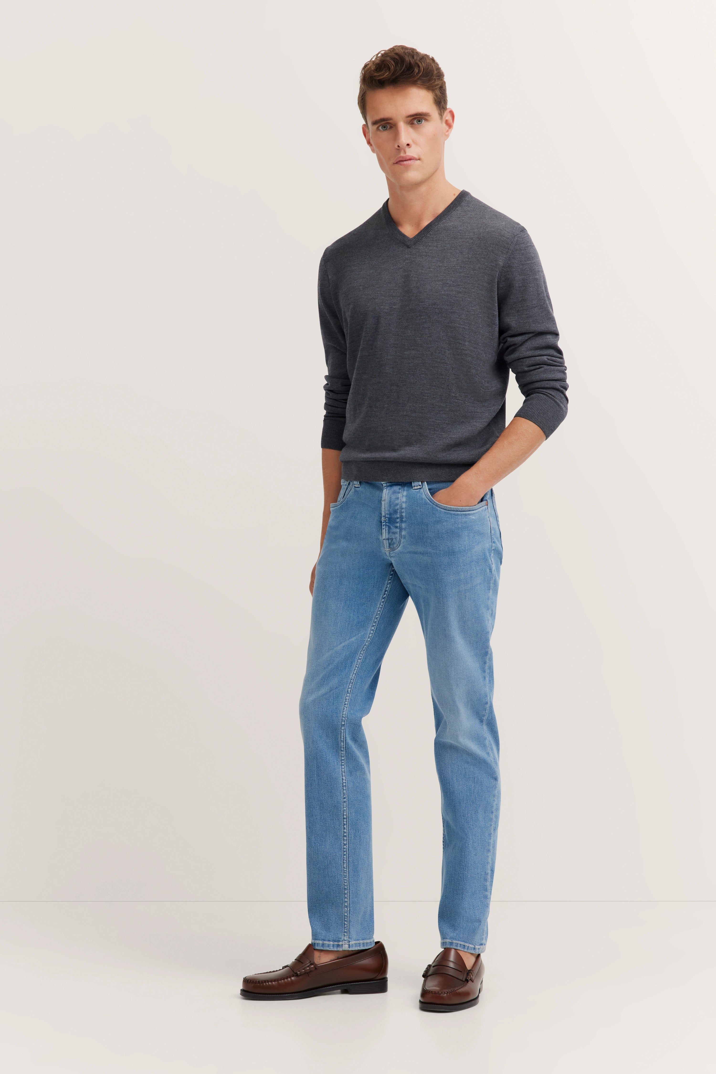 Bugatti legeres Outfit: grauer Pullover, blaue Jeans, braune Schuhe, Modelbild von hinten.