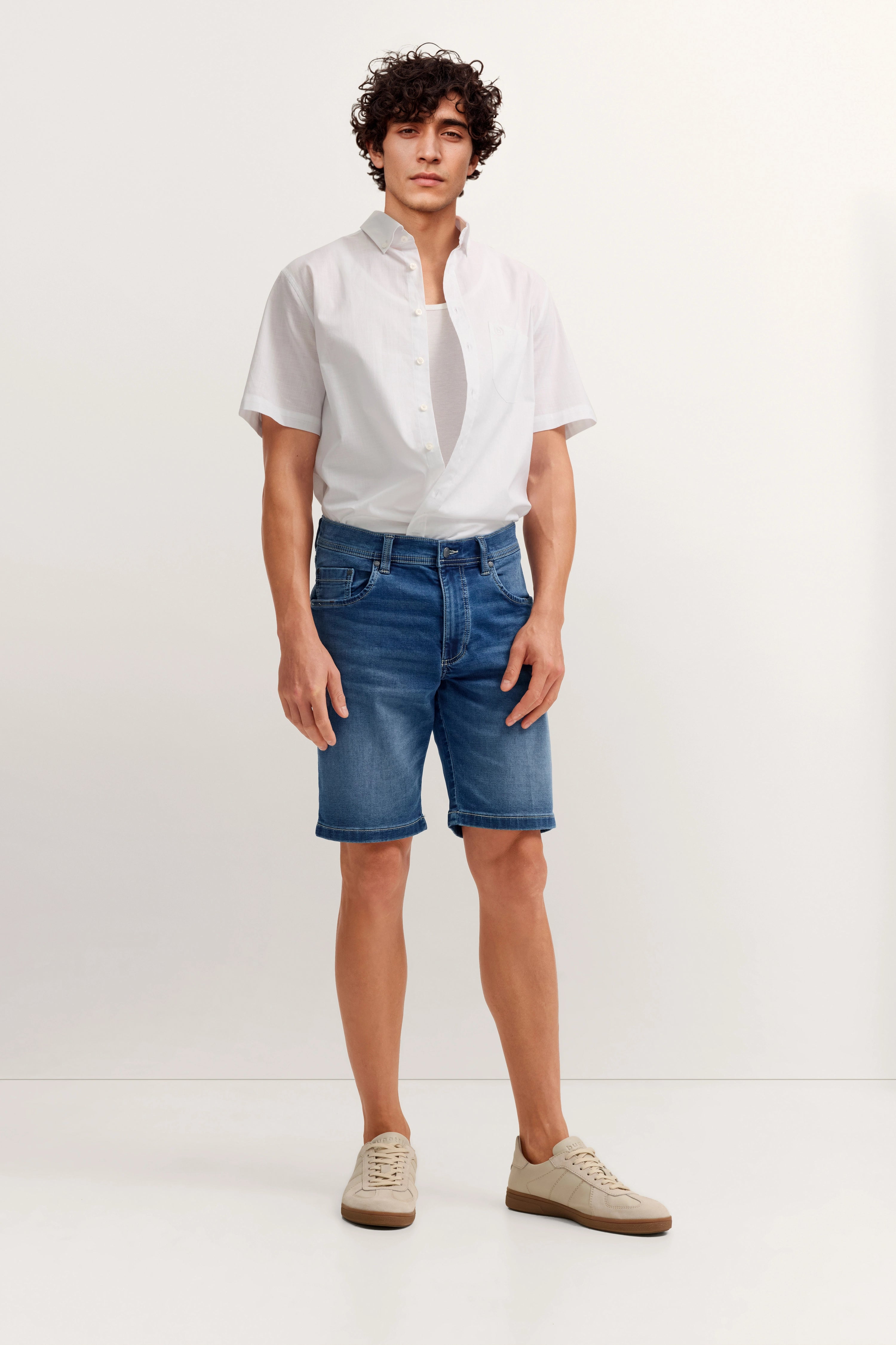 Weißes Kurzarmhemd, blaue Jeansshorts, beigefarbene Sneaker