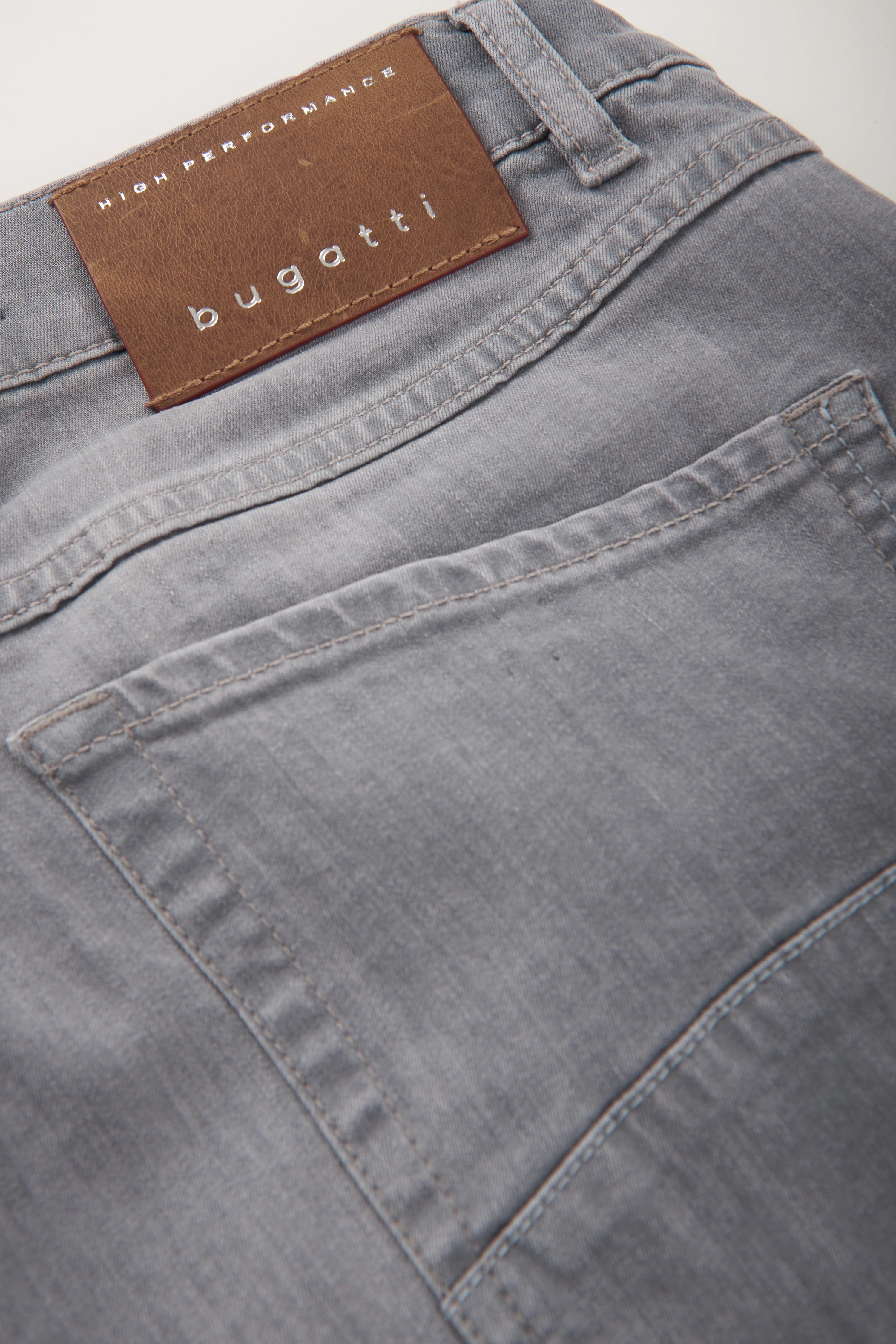 Grijze bugatti jeans met bruin leren label, detailaanzicht.