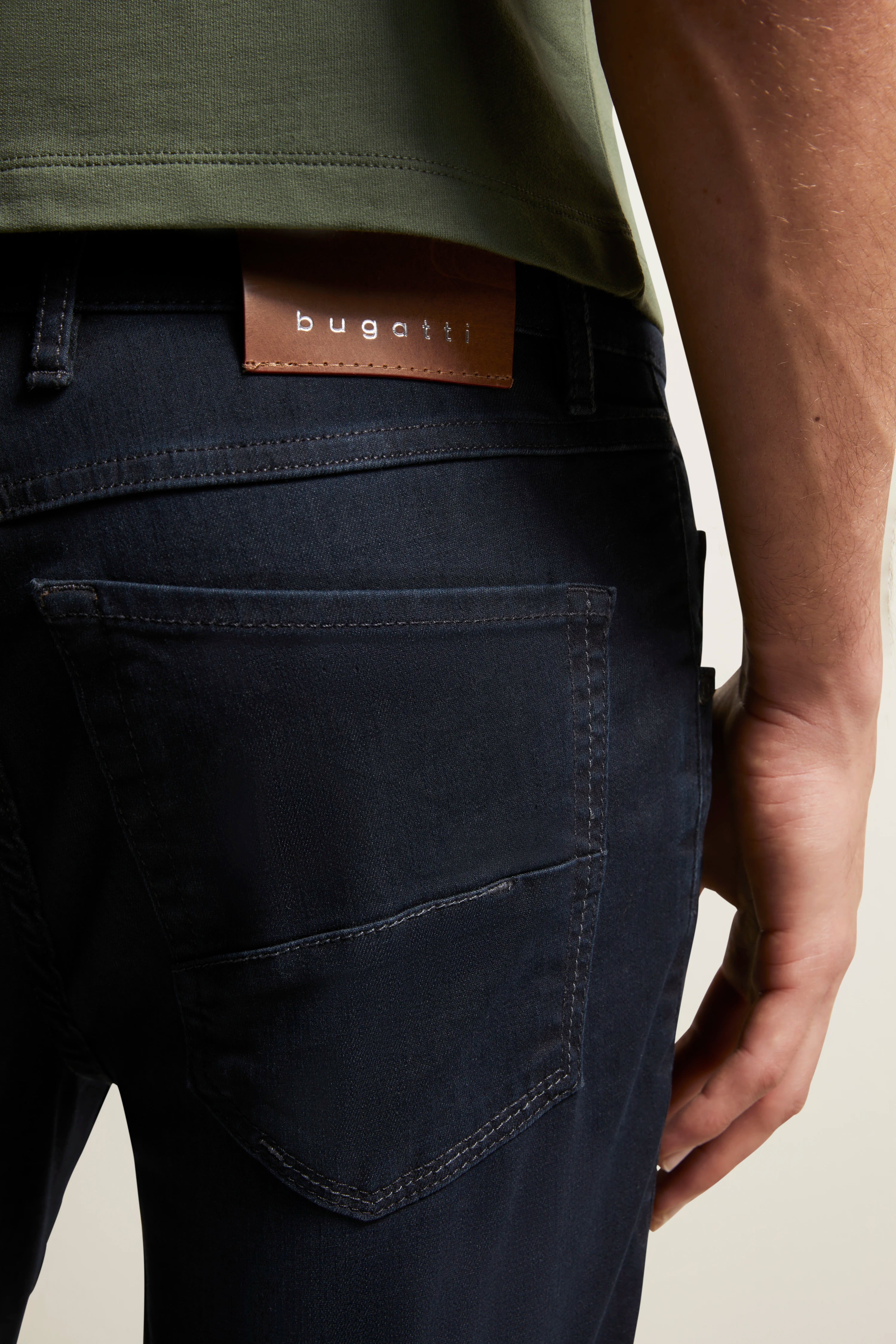 Donkerblauwe bugatti jeans, detail met groen shirt. Casual, stedelijke stijl.
