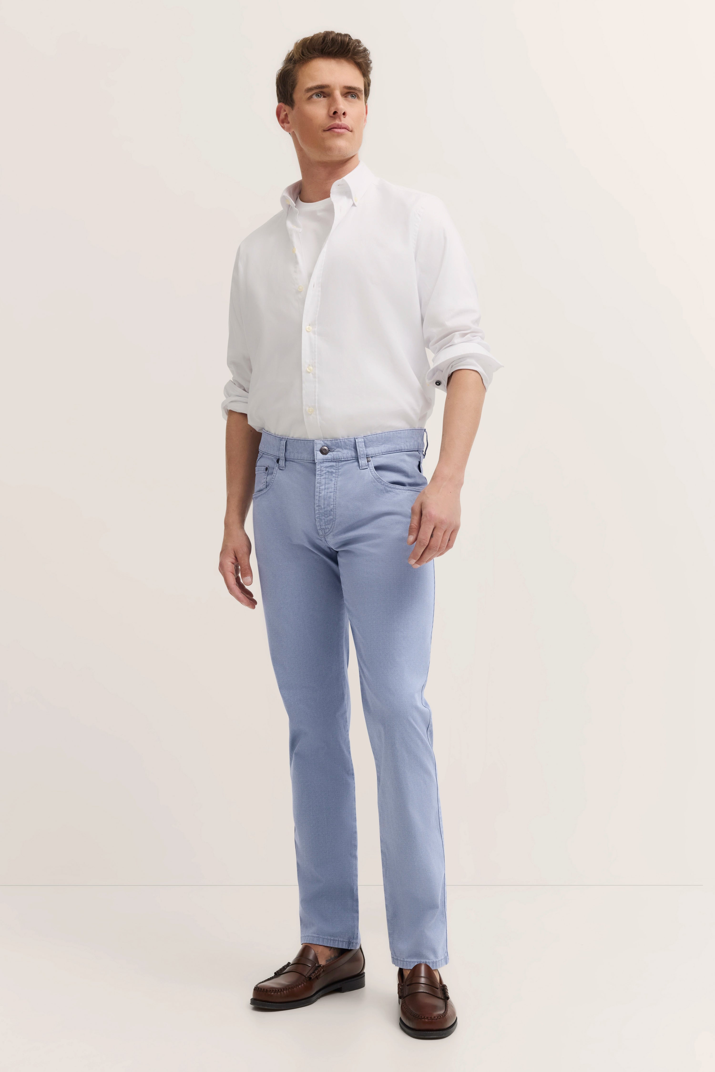 Wit hemd, lichtblauwe broek, bruine schoenen, model poseert staand, licht zijwaarts, bugatti.