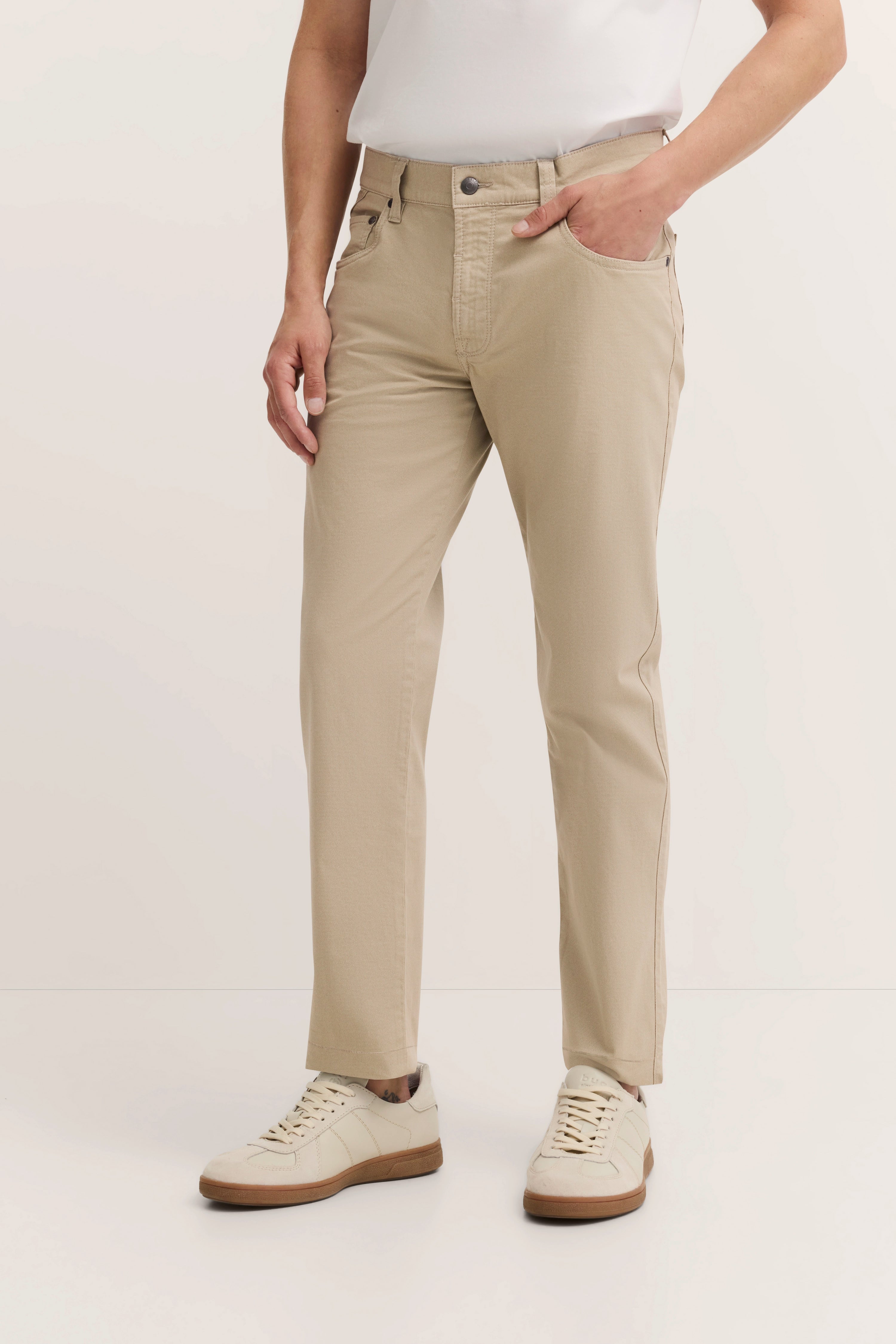 Beige bugatti broek, casual model, handen in zakken, witte sneakers.