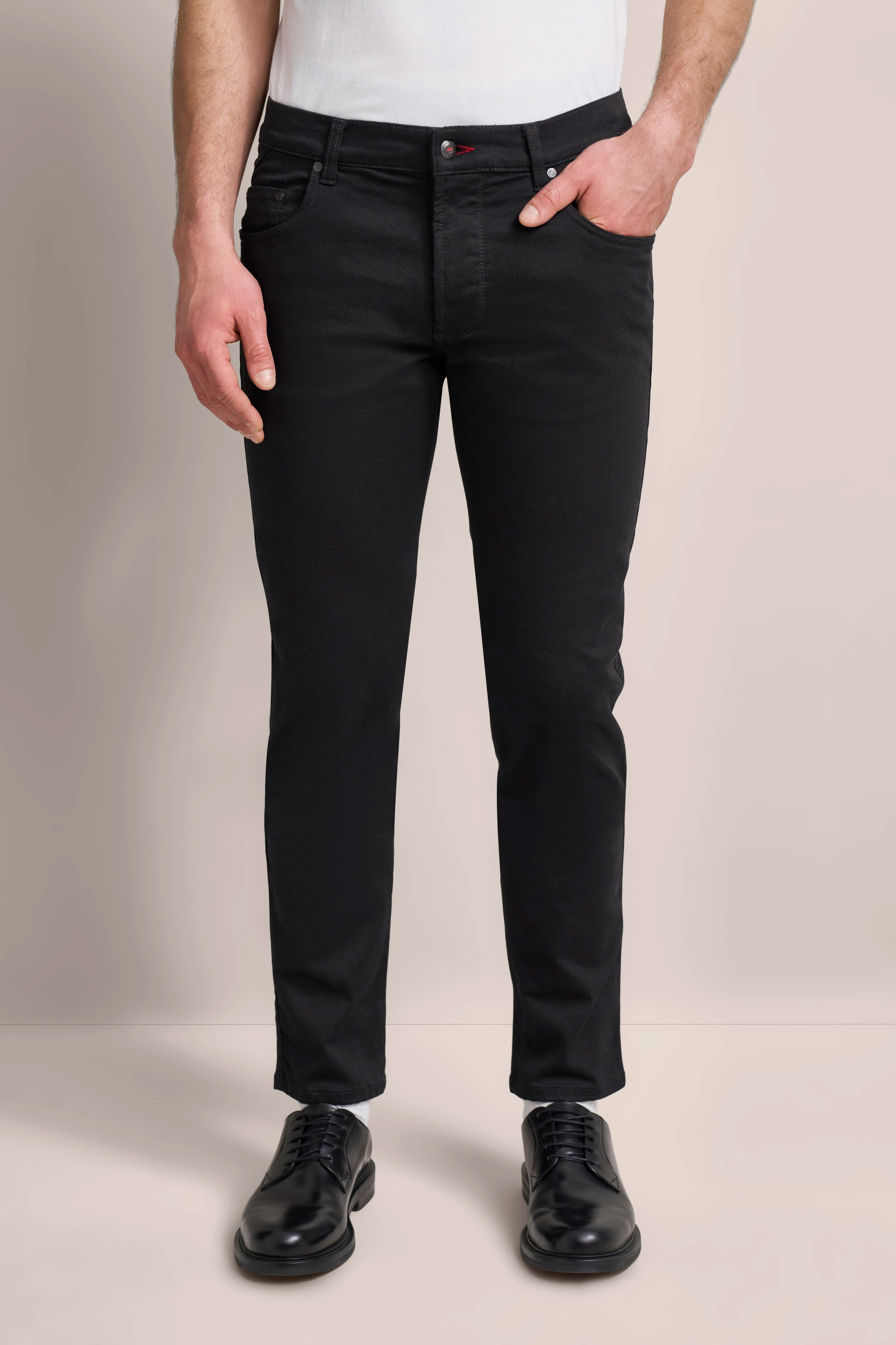 Schwarze bugatti Jeans mit weißem Shirt, legeres Modelbild, entspannte Pose, zeitlos elegant.