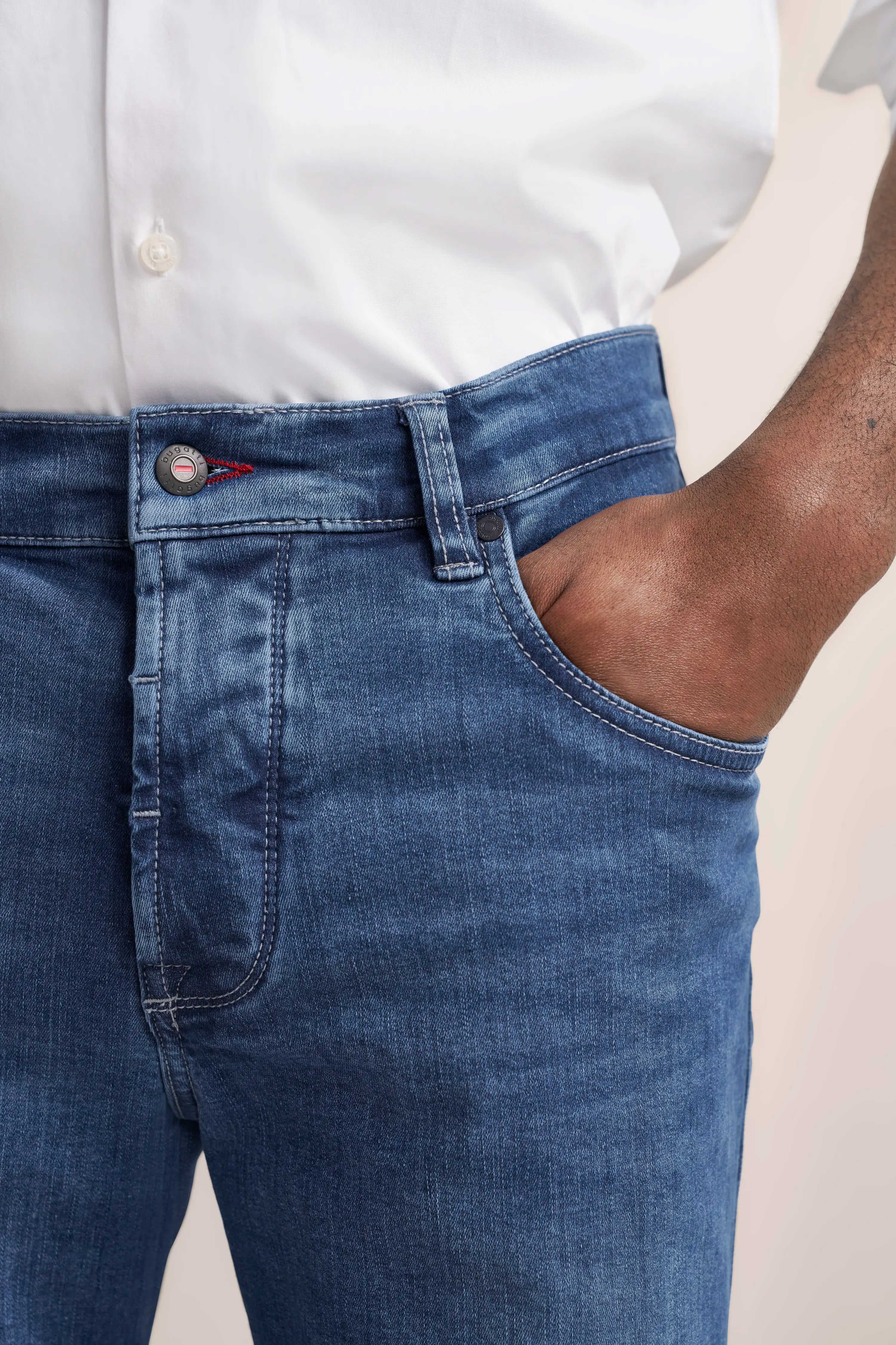 Jeans in Blau, legeres Bild, Hand in der Tasche, weißes Hemd sichtbar.