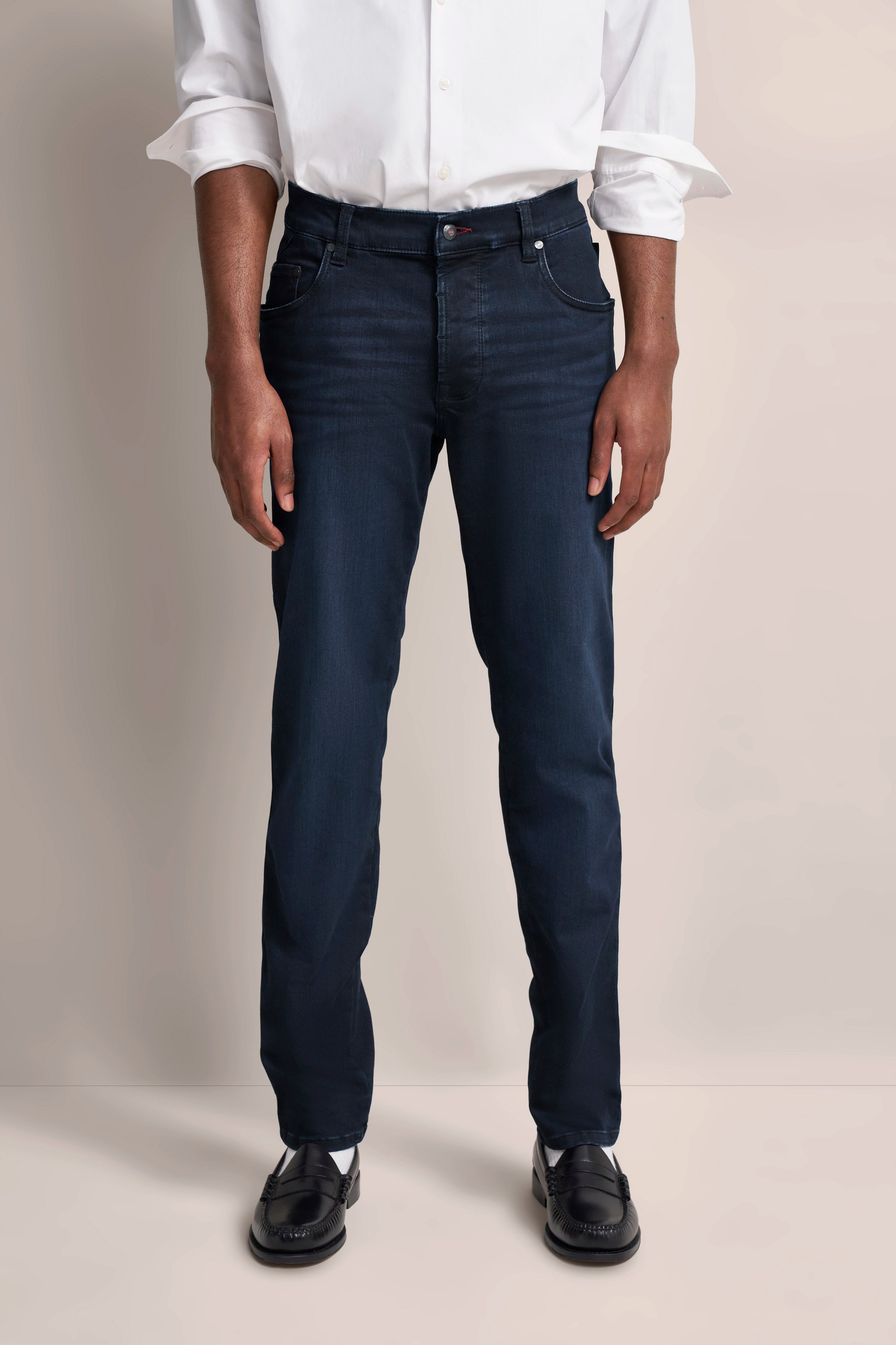 Weißes Hemd und dunkelblaue Jeans von bugatti, legeres Modelbild, entspannte Pose.