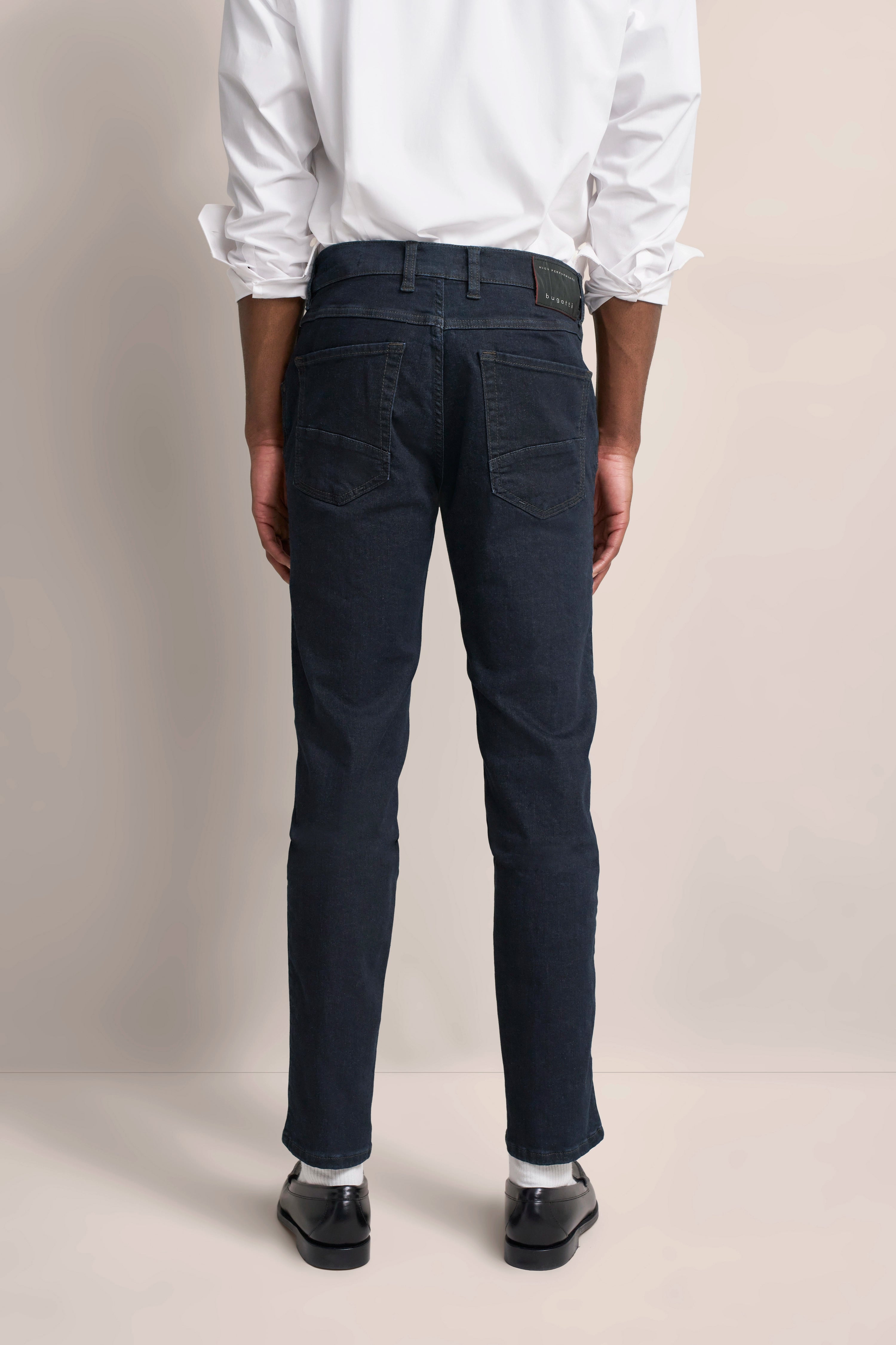 bugatti Modelbild: Weißes Hemd und dunkelblaue Jeans, Rückenansicht, Model steht gerade.