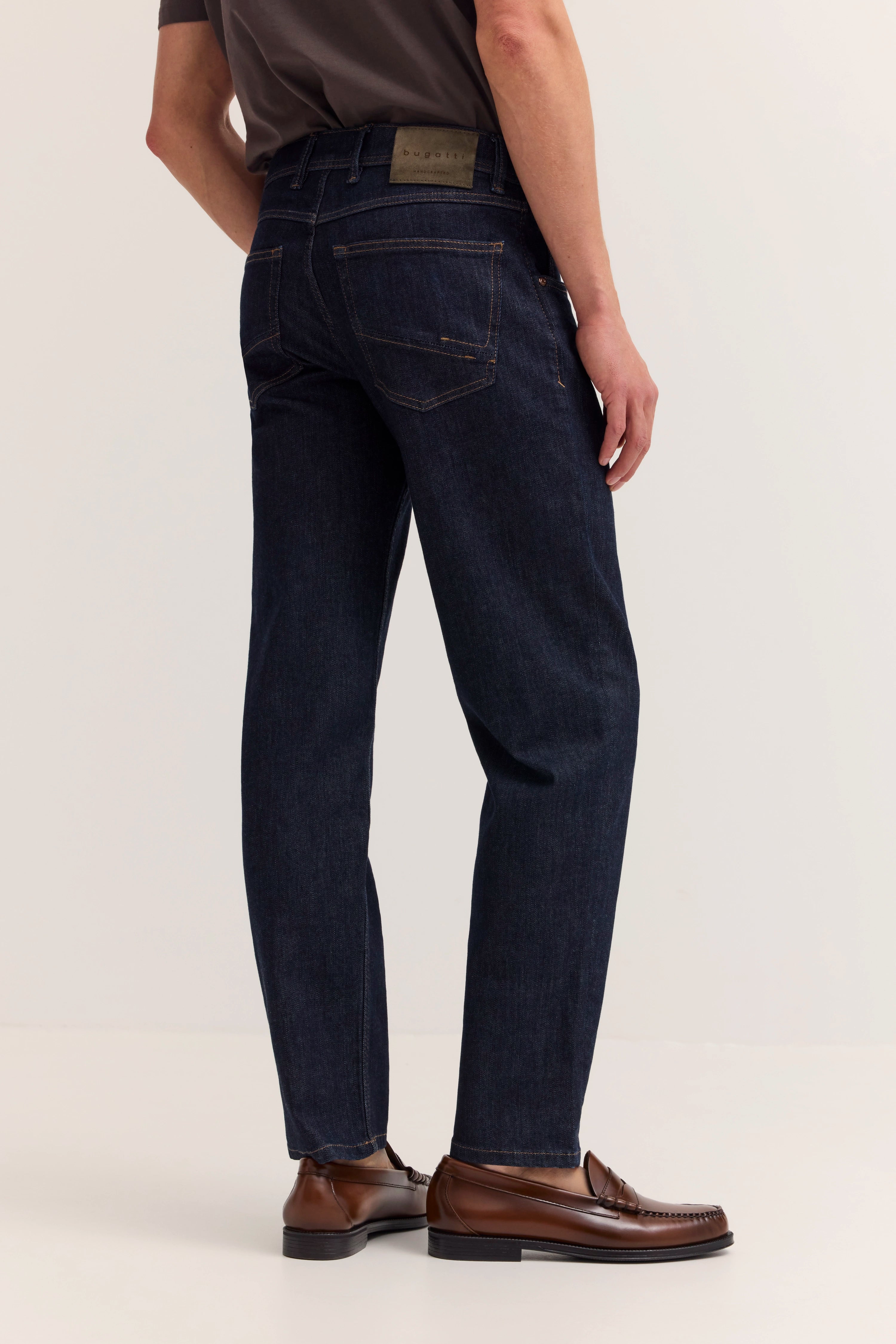 Dunkelblaue bugatti Jeans, braune Loafer, Modelbild, seitliche Ansicht.