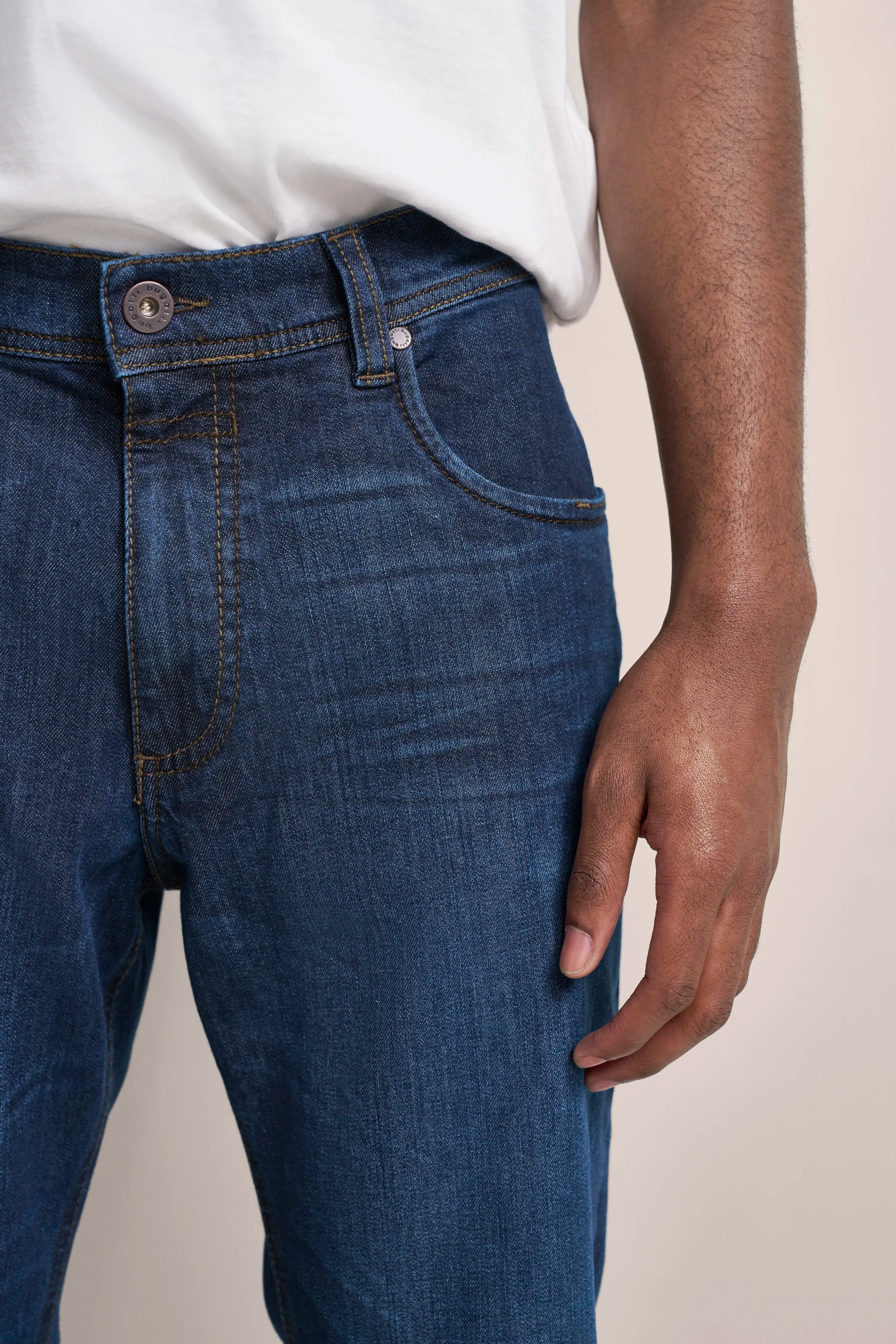 bugatti Jeans in Dunkelblau, leger getragen mit weißem T-Shirt, Detailansicht.