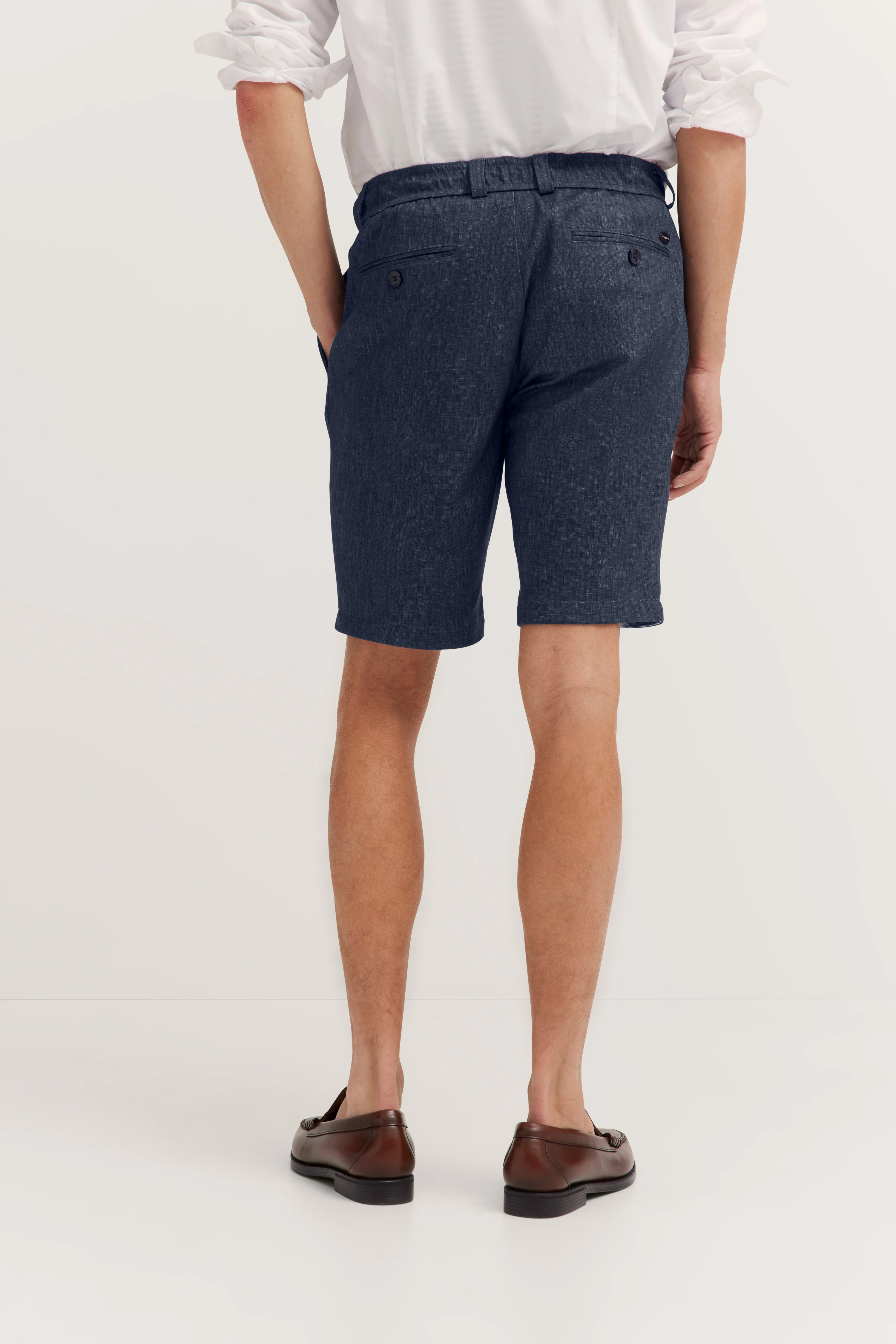 Weißes Hemd mit dunkelblauen Shorts und braunen Schuhen, Rückansicht, legeres Modelbild.