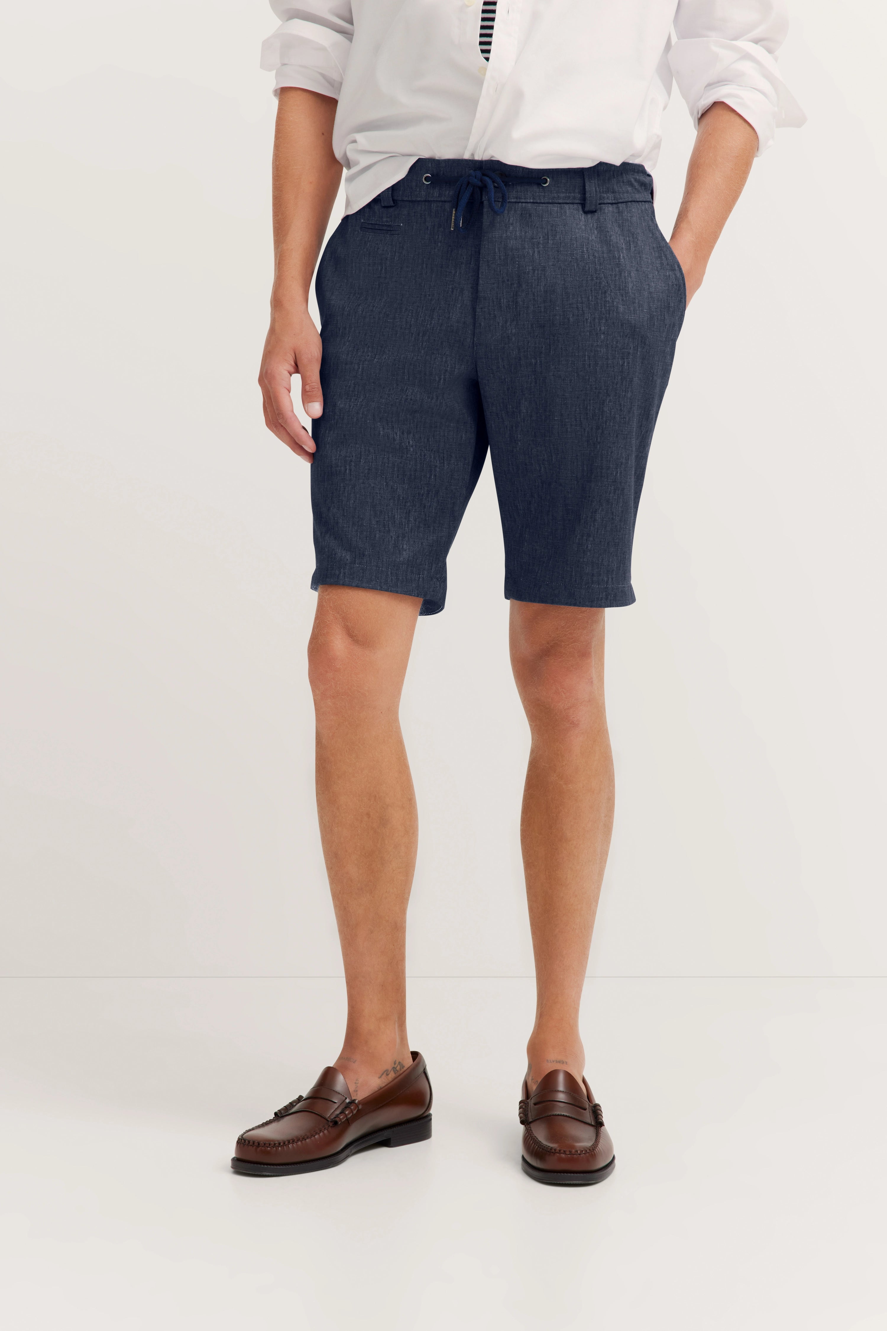 Weiße Hemd und blaue Shorts von bugatti, lässiges Modelbild mit legerer Pose.