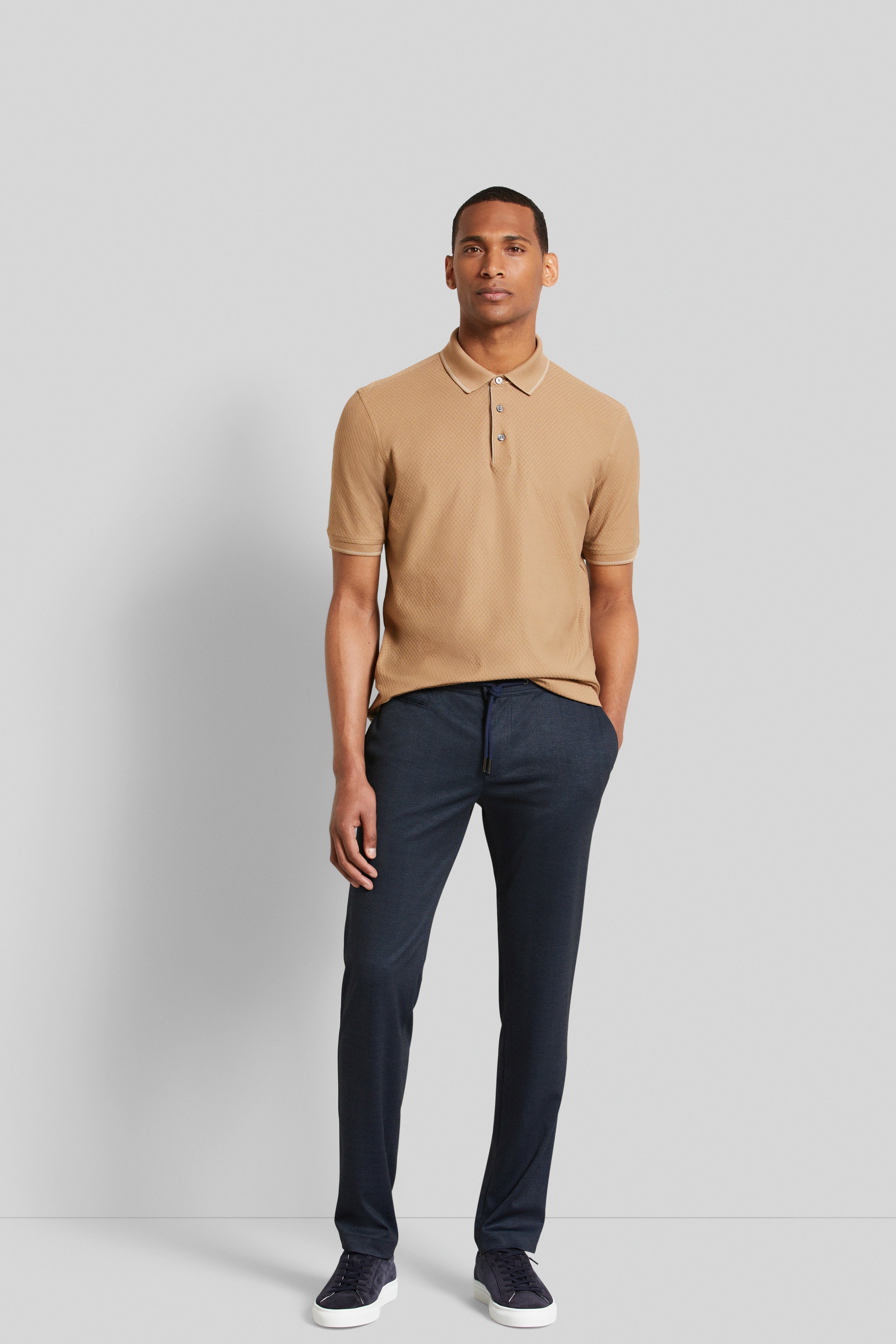 bugatti model: Beige polo, blauwe broek, casual houding, stijlvol en ontspannen.