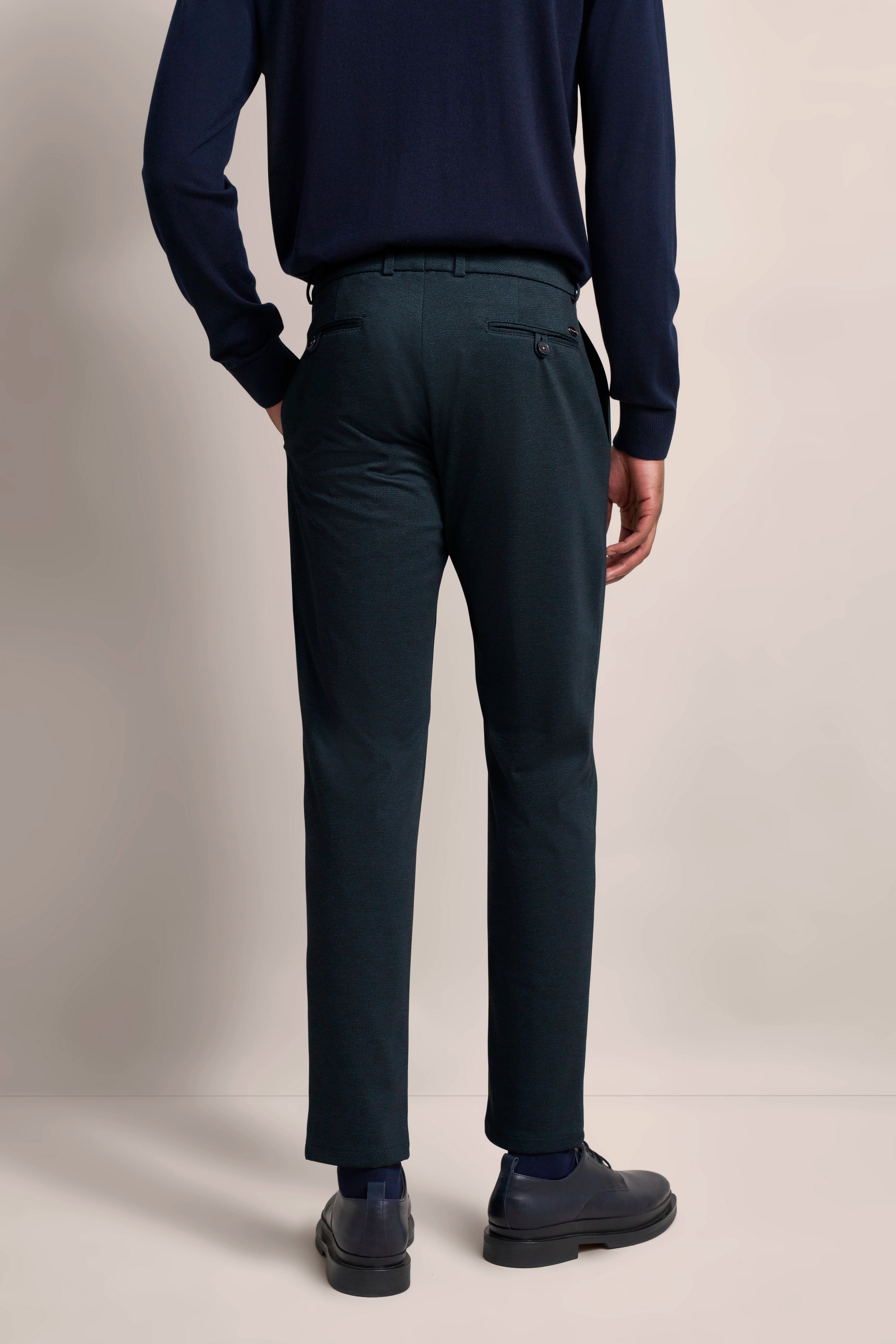Dunkelblauer Pullover, dunkelgraue Hose, Model von hinten stehend, bugatti Stil.