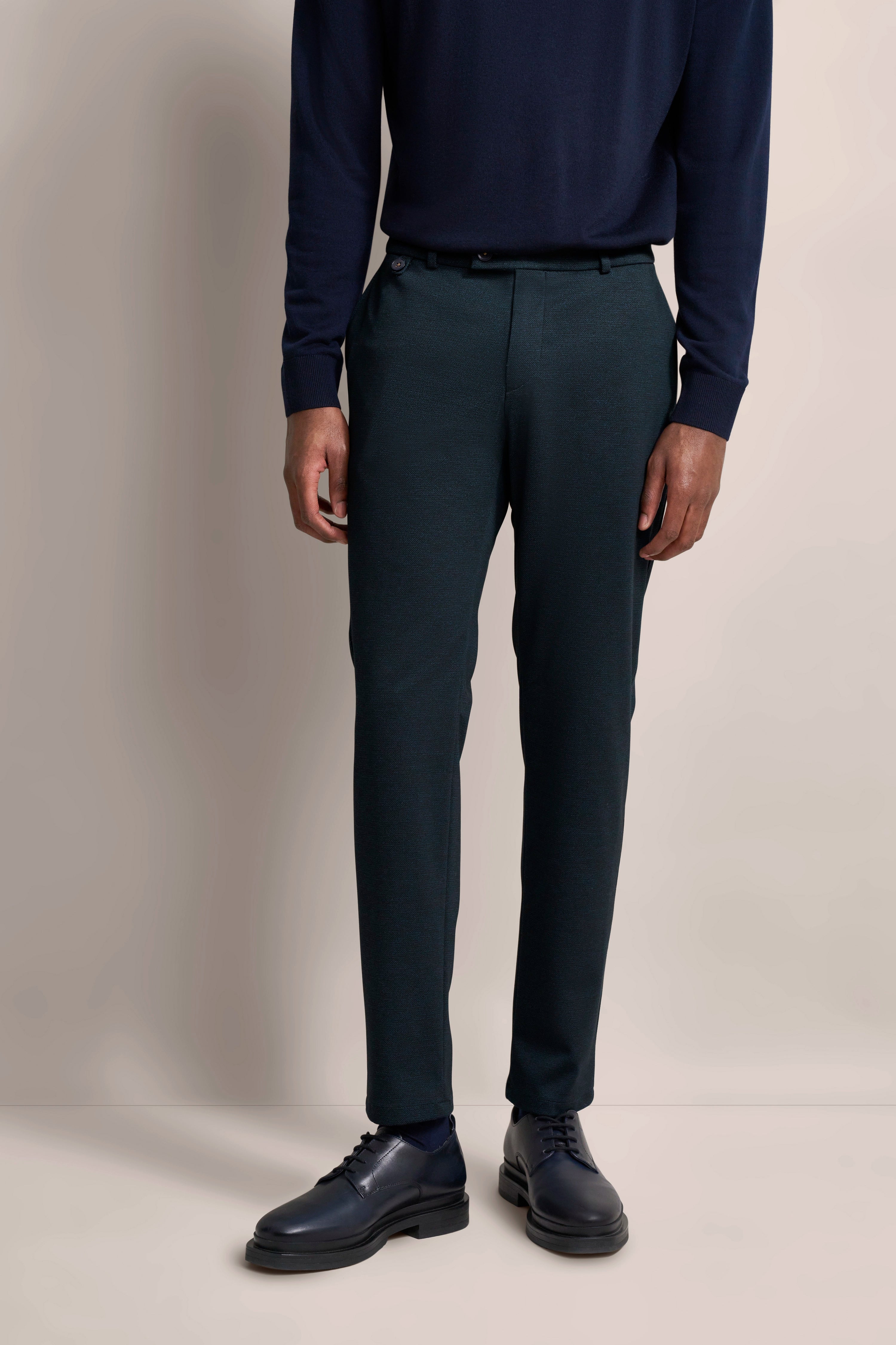 bugatti Herrenoutfit: Marineblauer Pullover, dunkelgrüne Hose. Modelbild, stehende Pose.