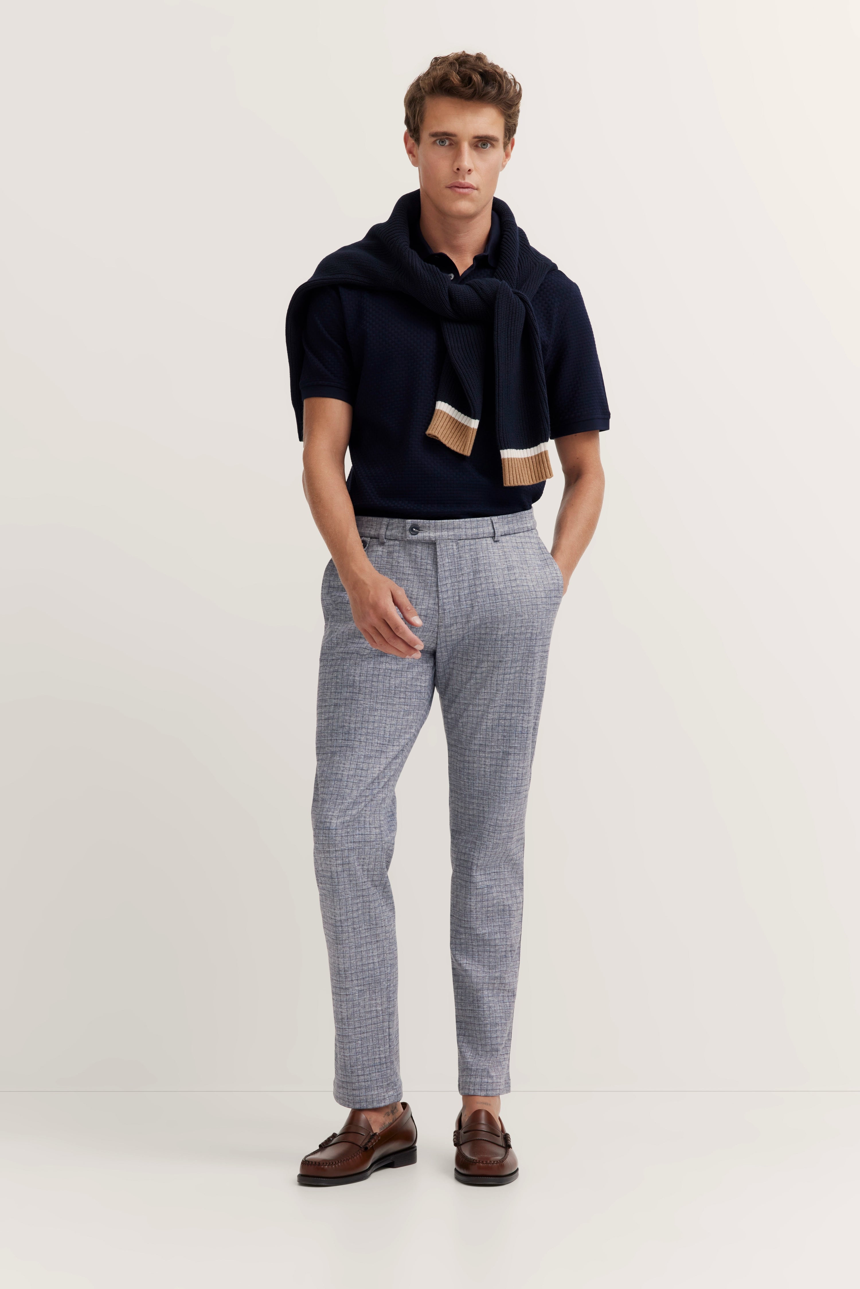 Marineblauw polo, blauwe trui, grijze broek, bruine schoenen, model staand, bugatti stijl.