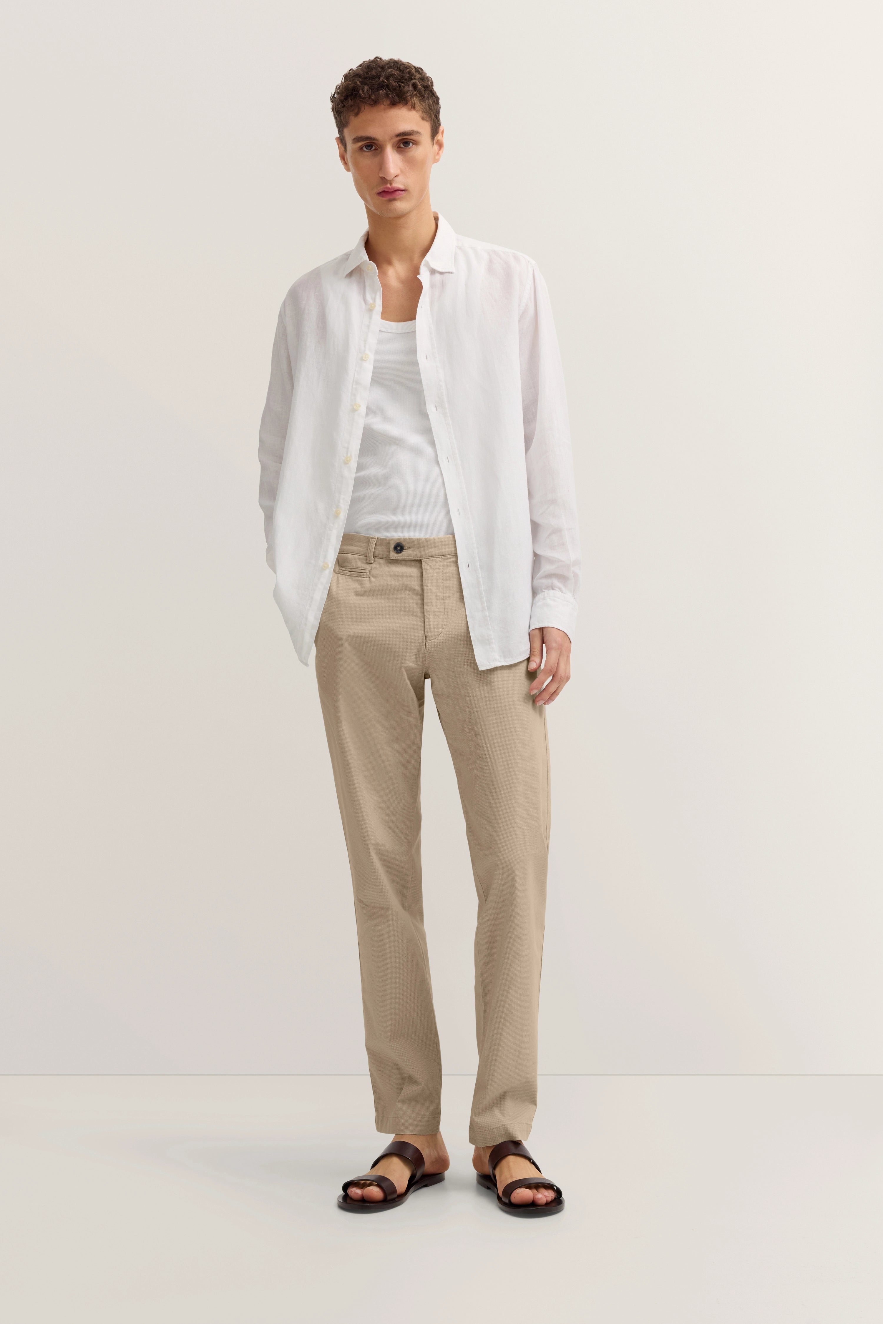 Weißes Hemd, beiges Chino, Model stehend, relaxte Pose, bugatti Stil und Geschmackssicherheit.