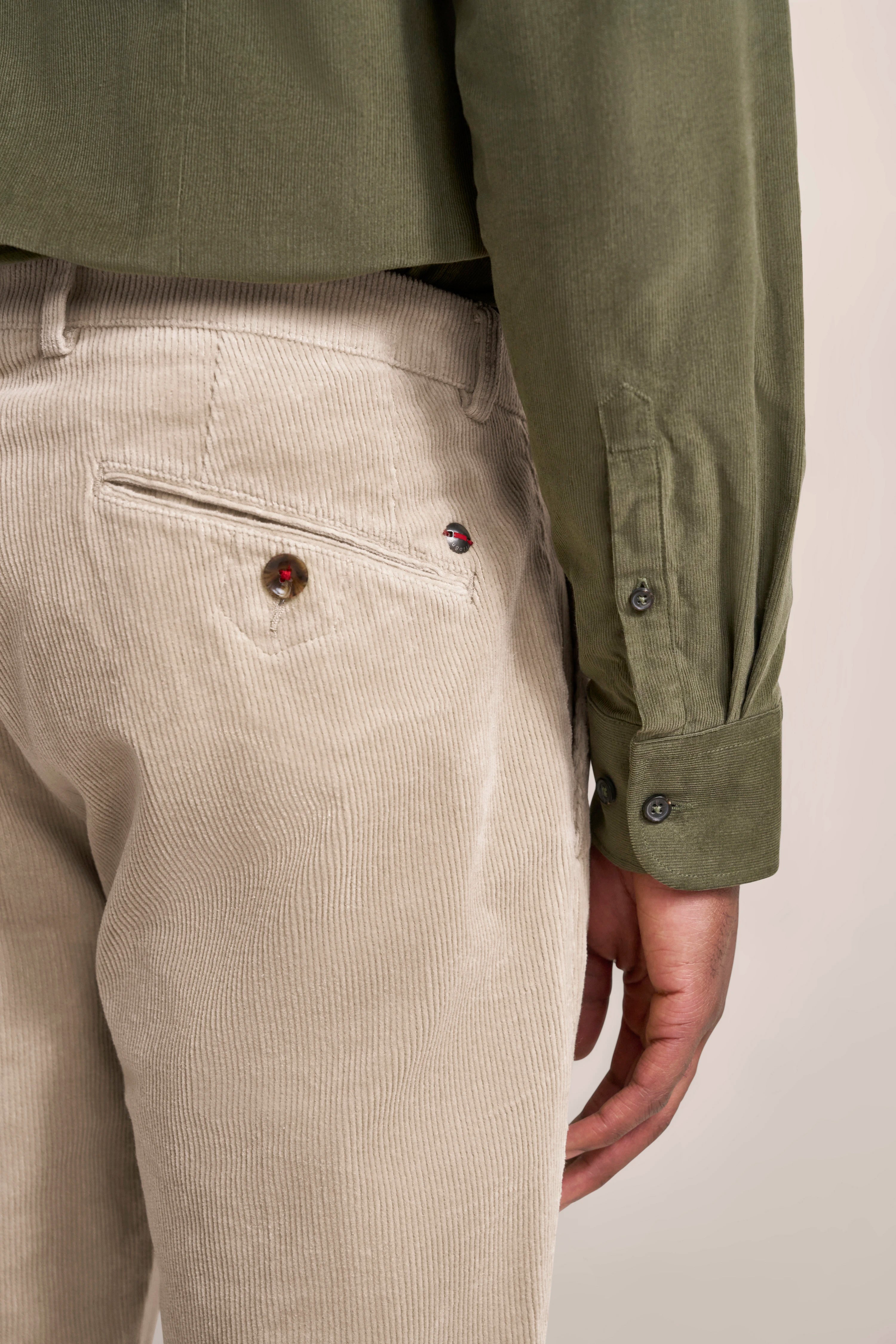 Grünes Hemd mit beigefarbener Cordhose, legeres Büstenbild.