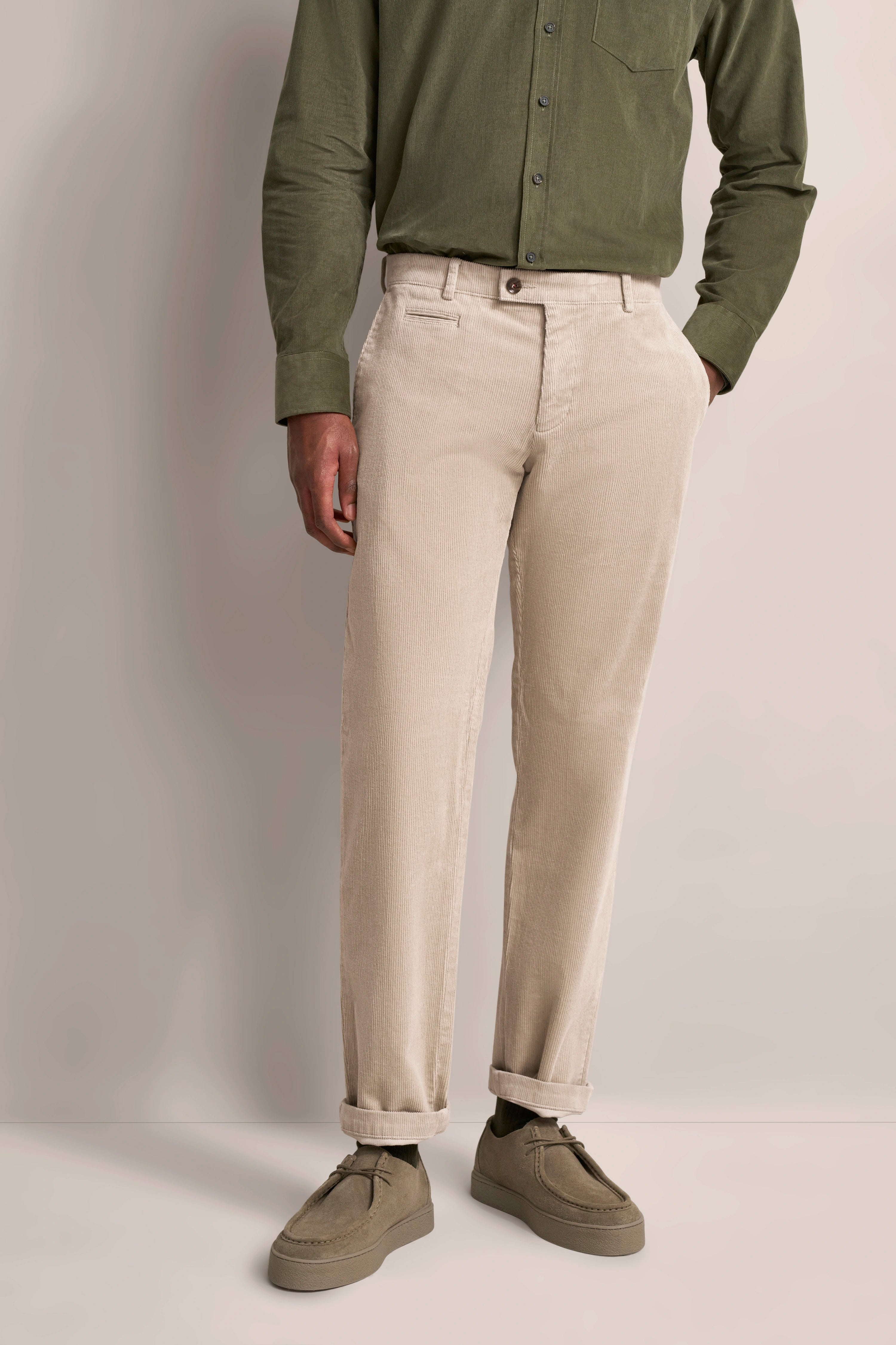 Grünes Hemd und beige Hose, legeres Modelbild, entspannte Pose.