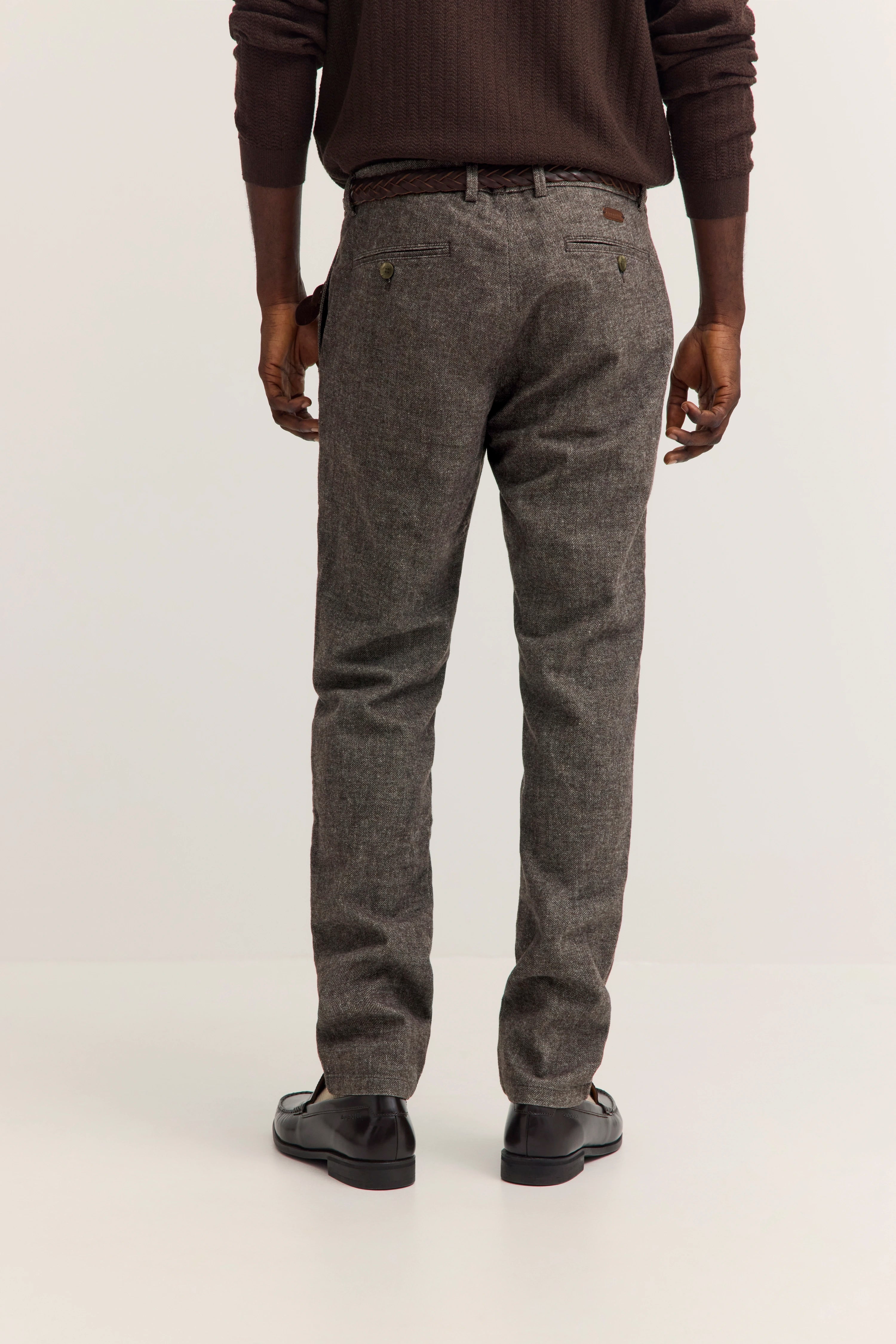 bugatti Modelbild, Mann in grauer Hose und braunem Pullover, Rückenansicht, entspannte Pose.