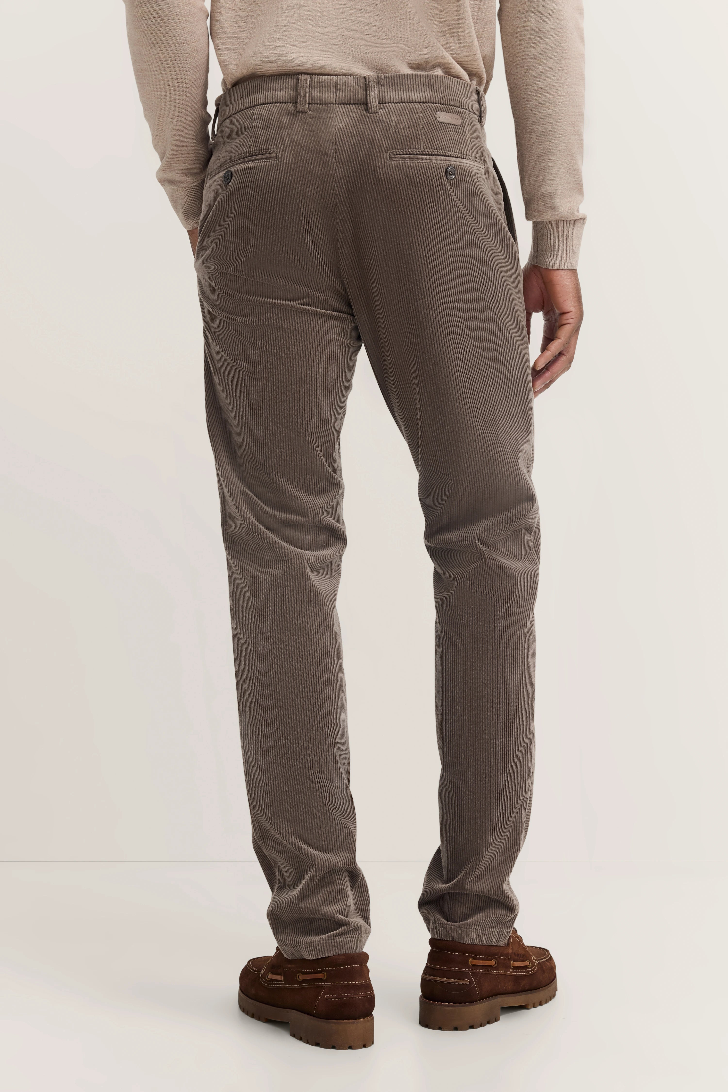Herrenmodell in brauner Cordhose und beigem Pullover von bugatti, legeres Posing von hinten.