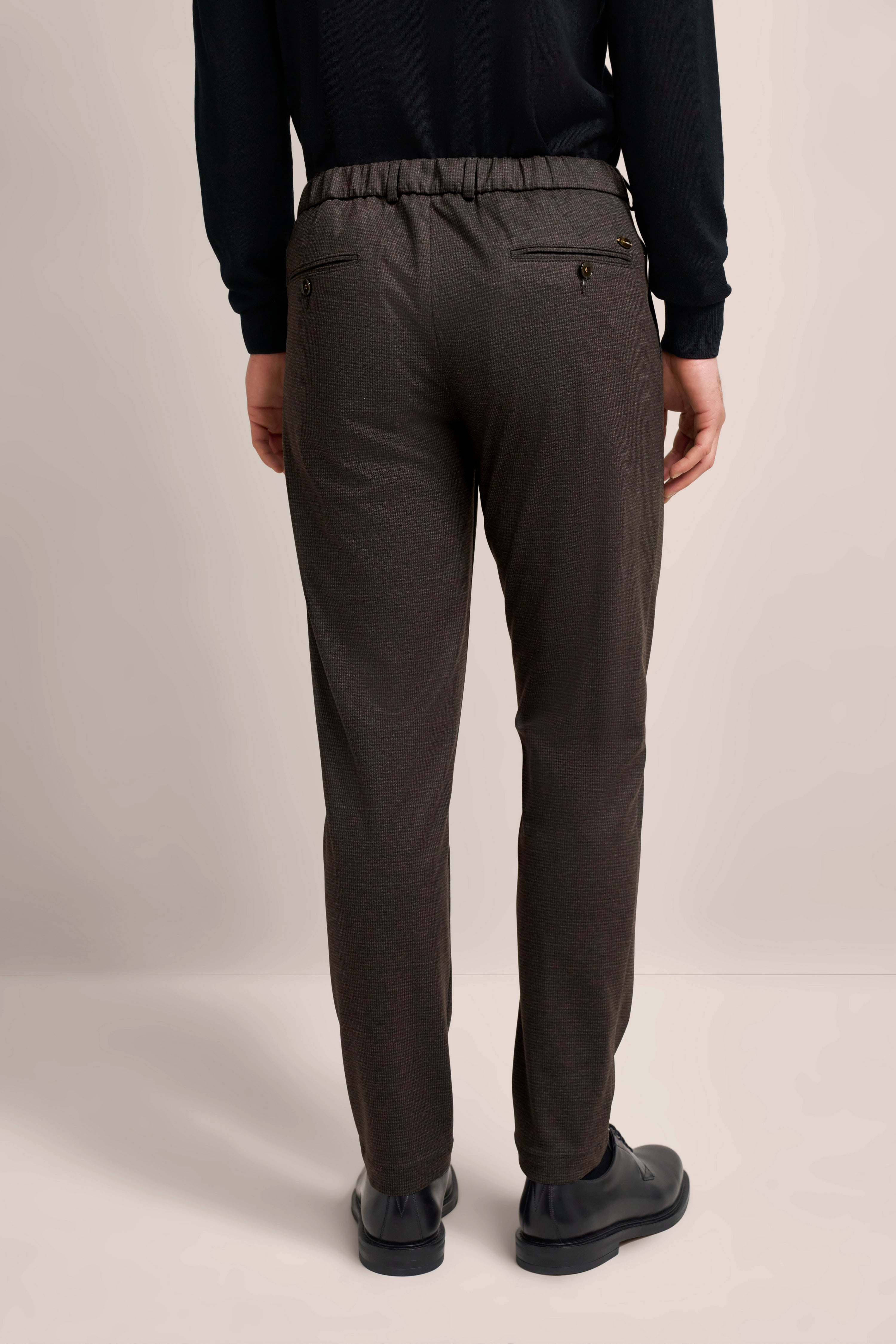 Graue gemusterte bugatti Hose, legeres Modelbild von hinten, schwarze Schuhe, entspannte Pose.