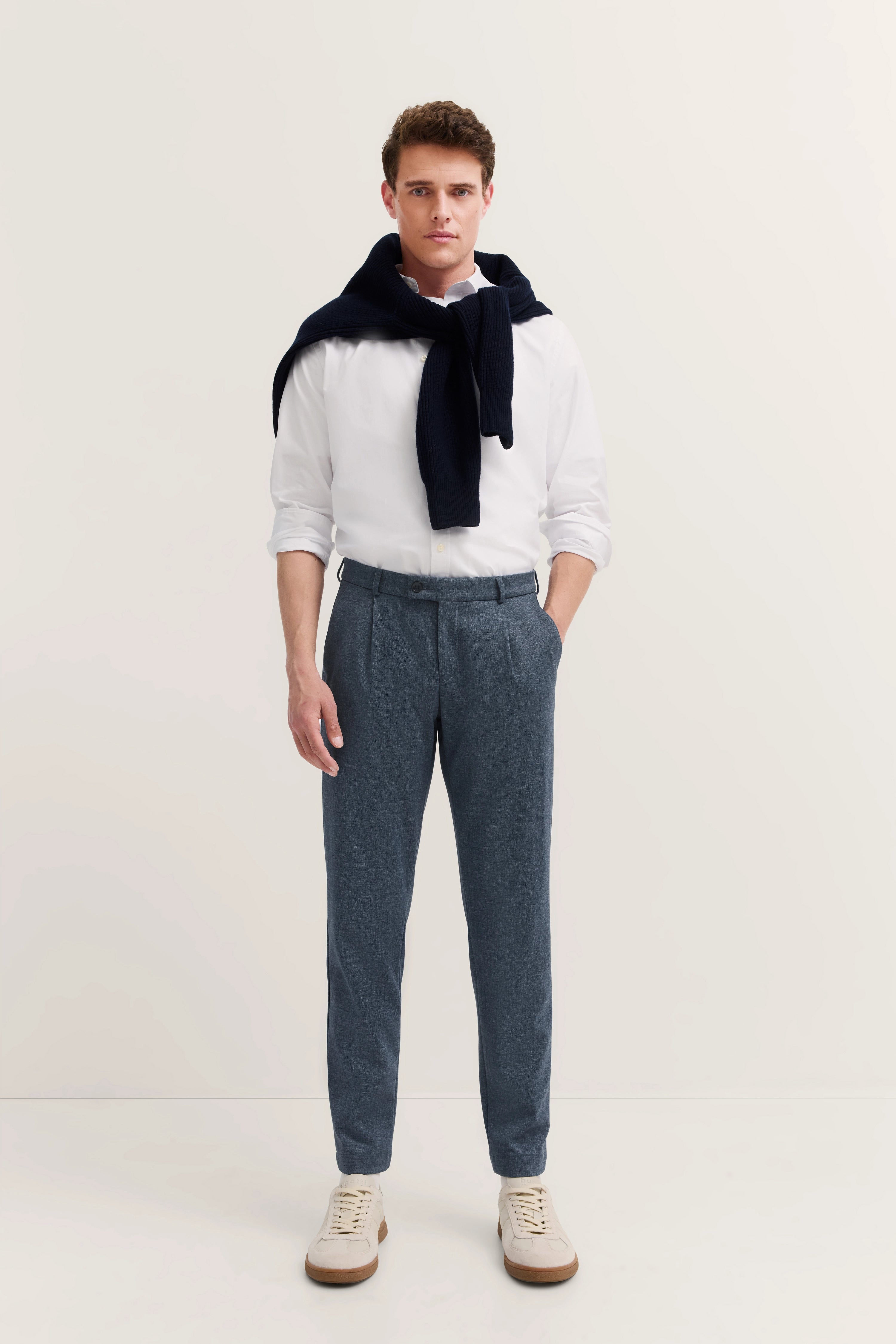 Blau gemusterte bugatti Hose in legerem Modelbild, Rückansicht mit weißem Hemd und Sneakers.