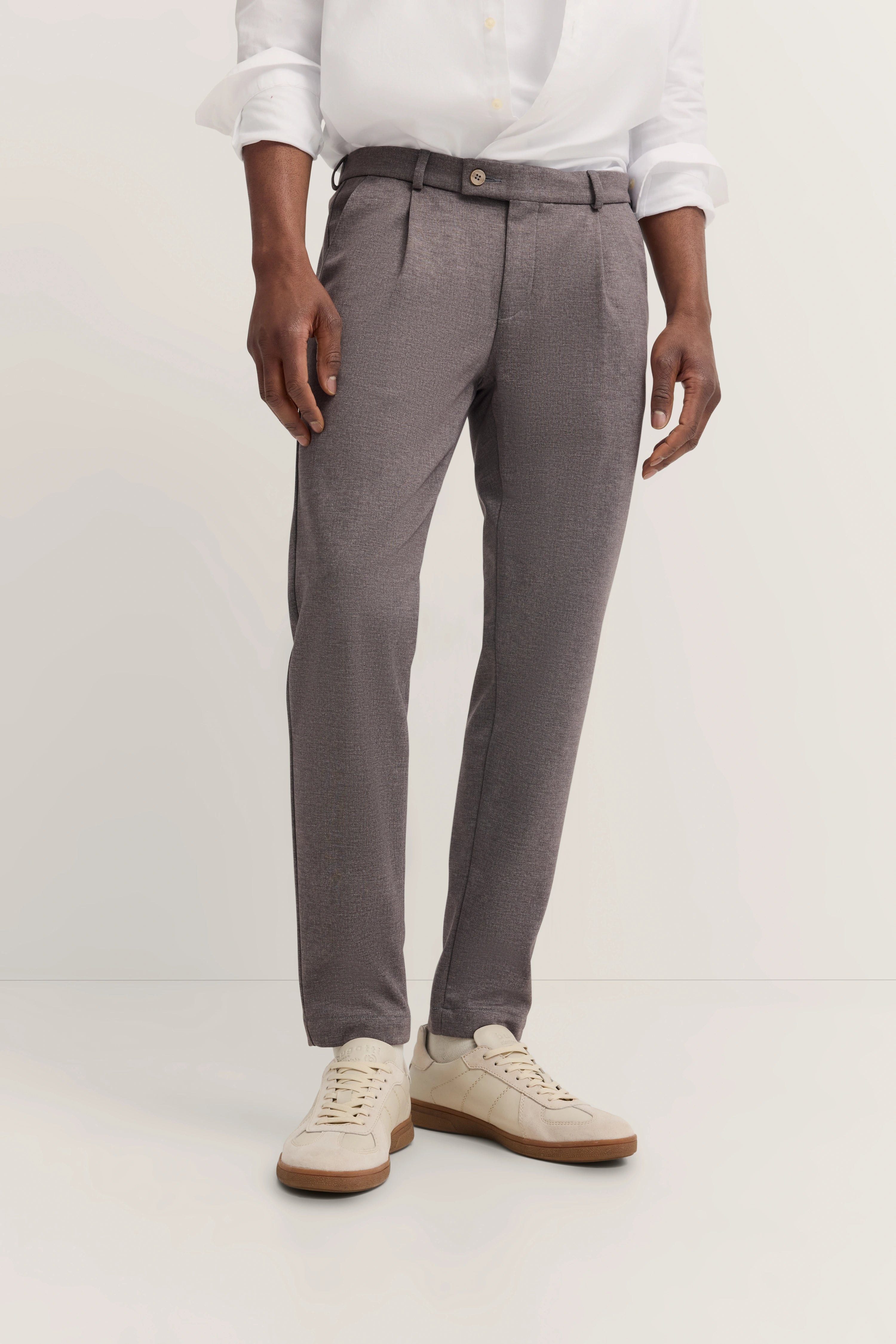 Graue Hose mit weißem Hemd, legeres Modelbild, entspannte Pose.