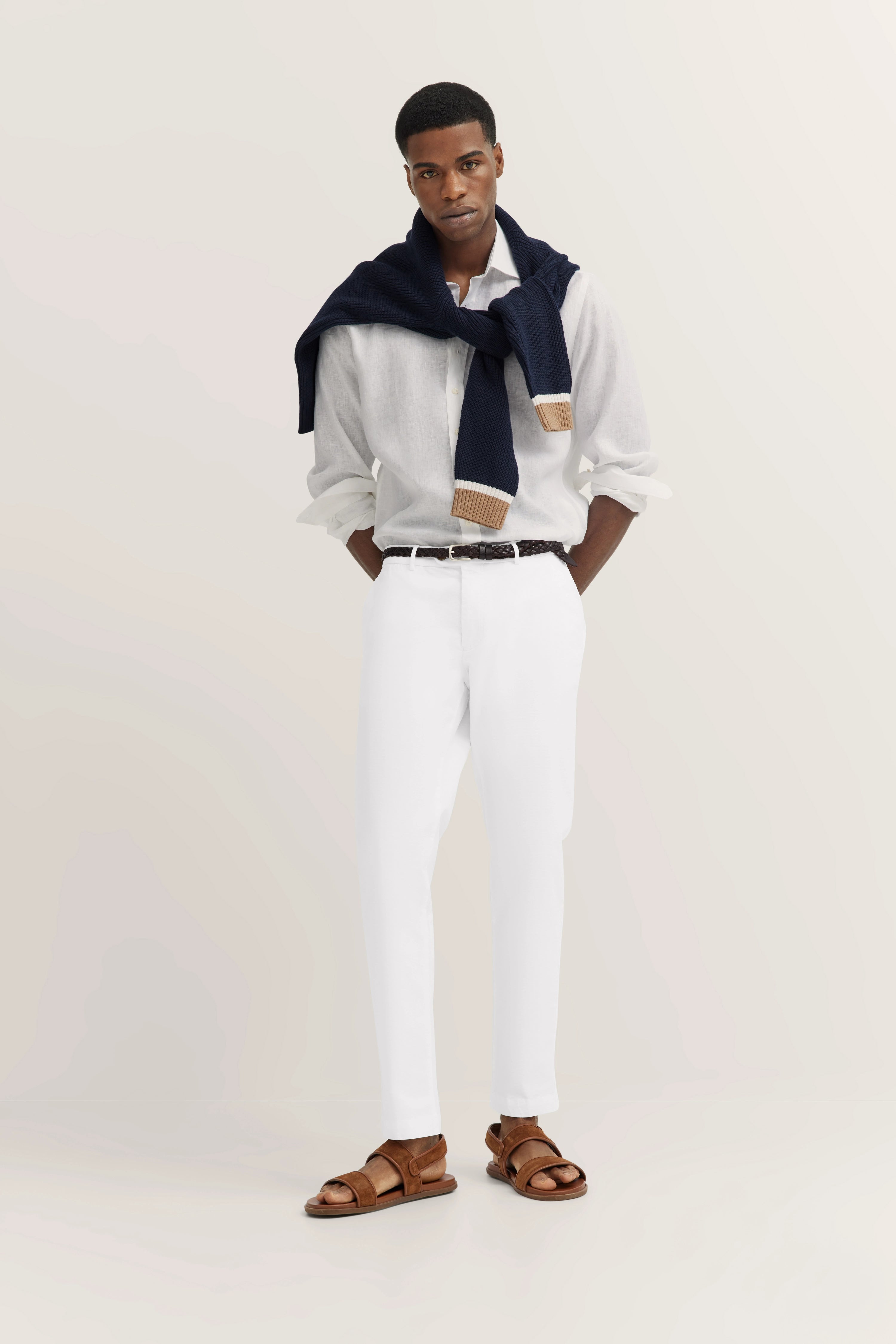Witte bugatti-broek, ontspannen model, achteraanzicht, gecombineerd met bruine sandalen.