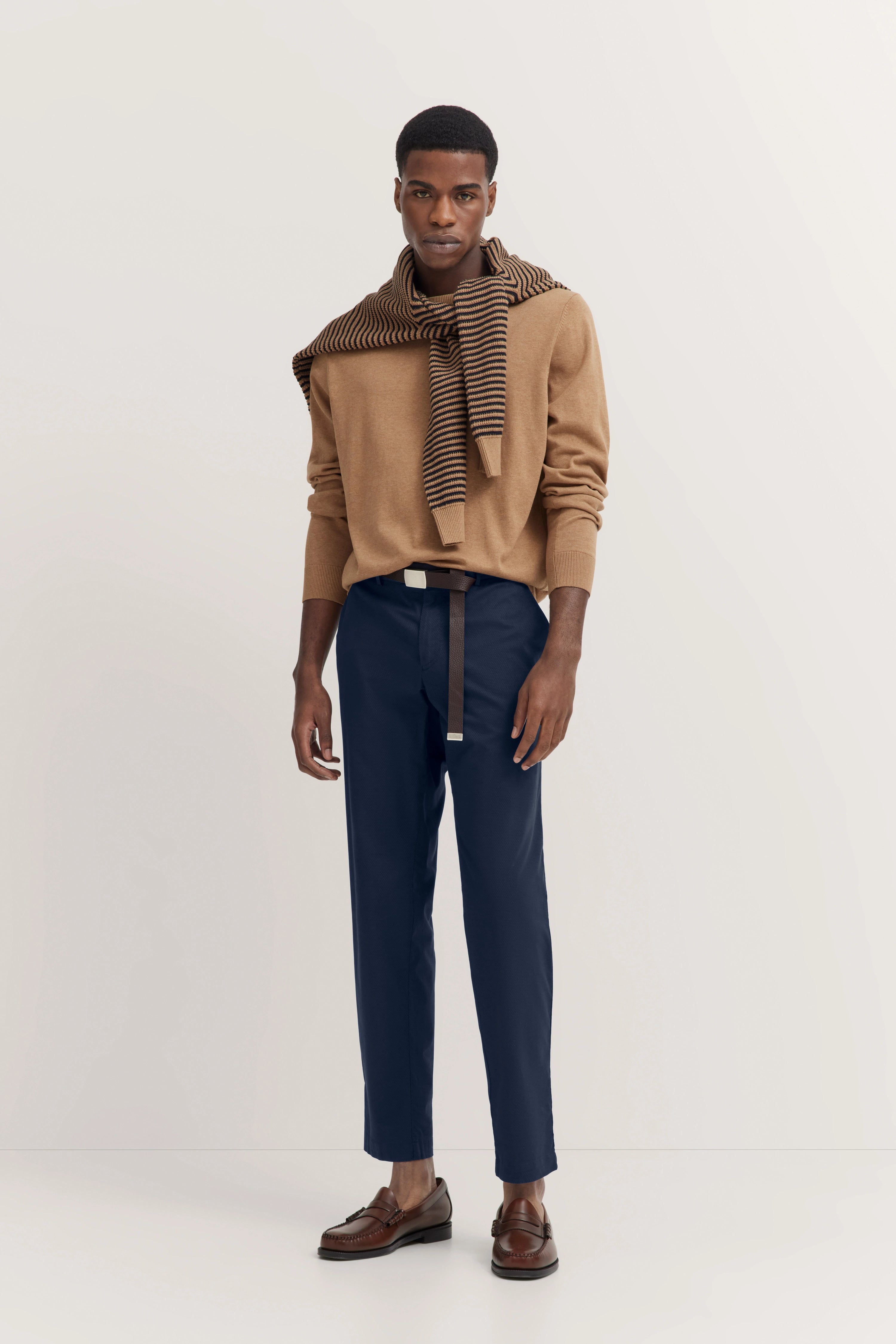 Model in camel Pullover und blauer Hose, gestreifter Schal, legeres Posing, bugatti Stil.