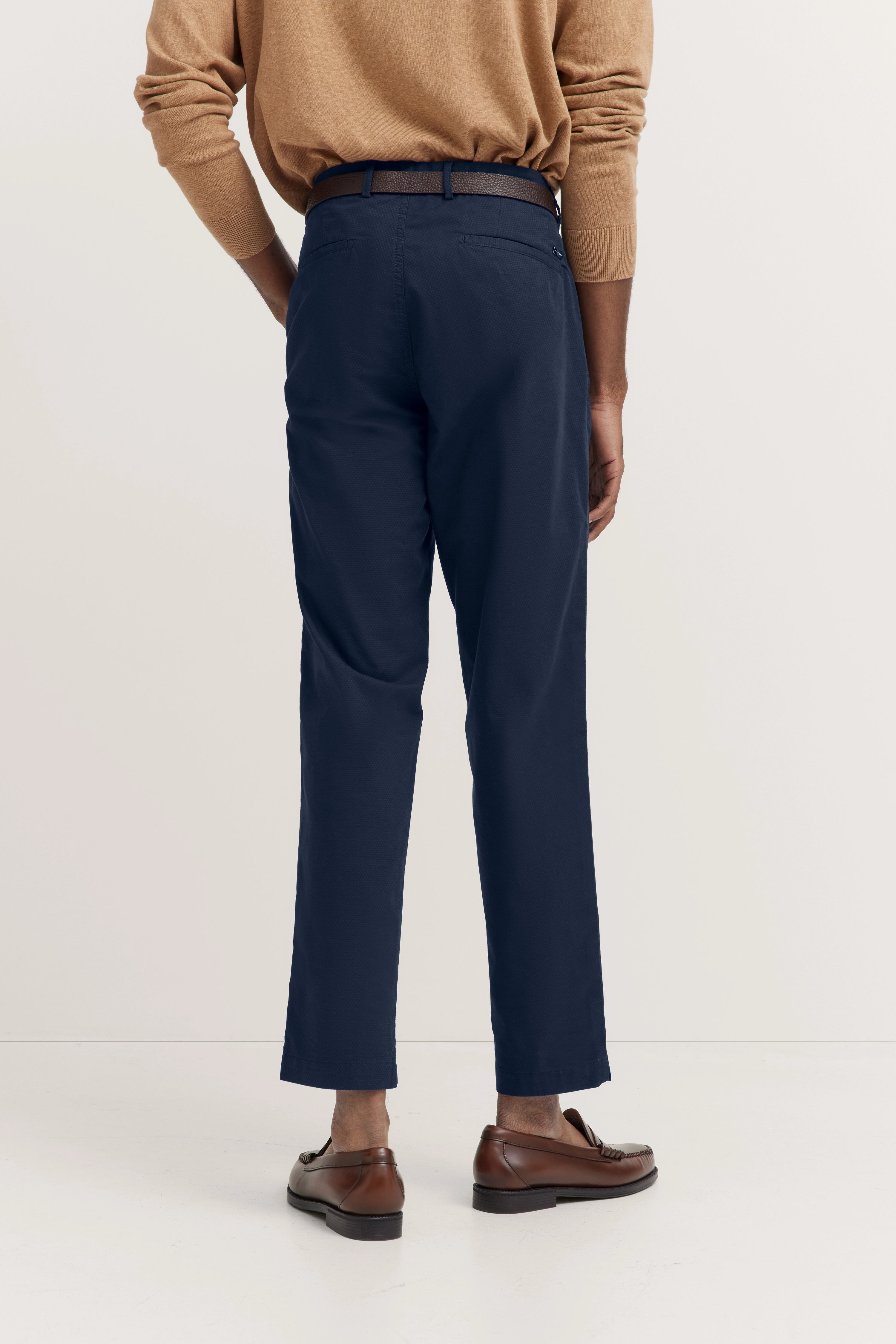 Beige Pullover und navy Hose, Modelbild von hinten, braune Schuhe, lässige Pose.