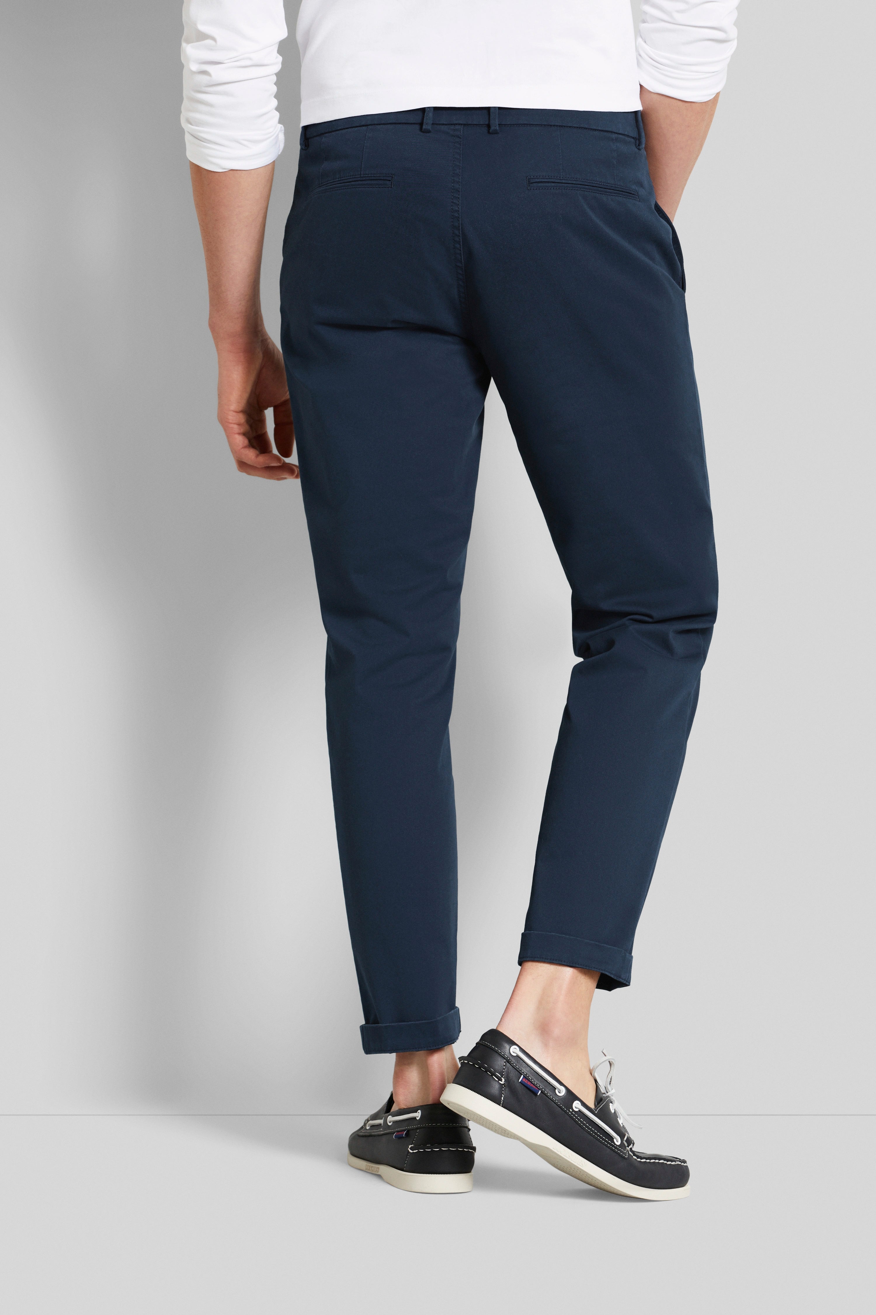 Marineblauwe chino's en zwarte bootschoenen, model van achteren in ontspannen pose, bugatti stijl.