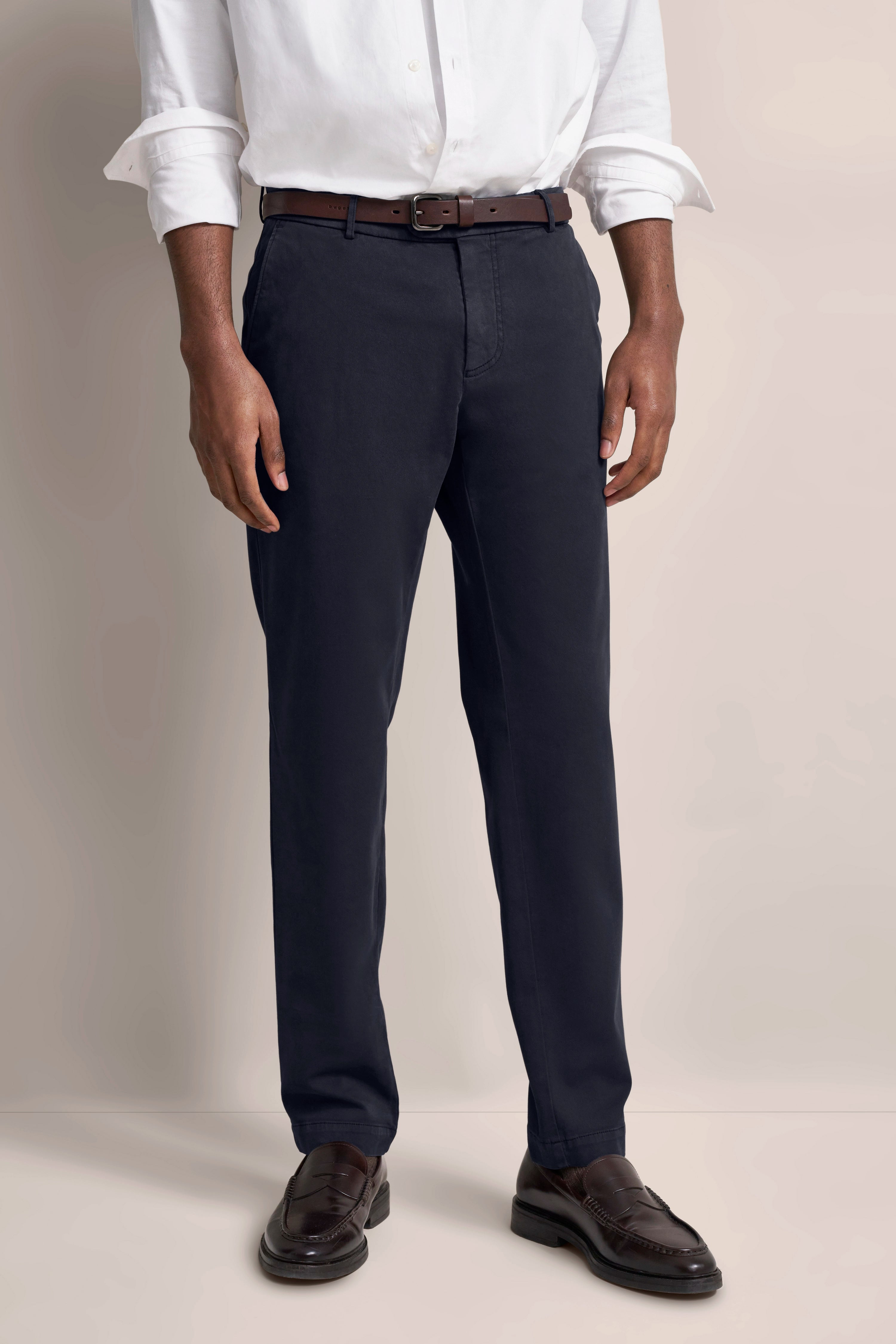 Hemd und Hose Outfit in Weiß und Dunkelblau, legeres Modelbild, Hände in Hosentaschen.