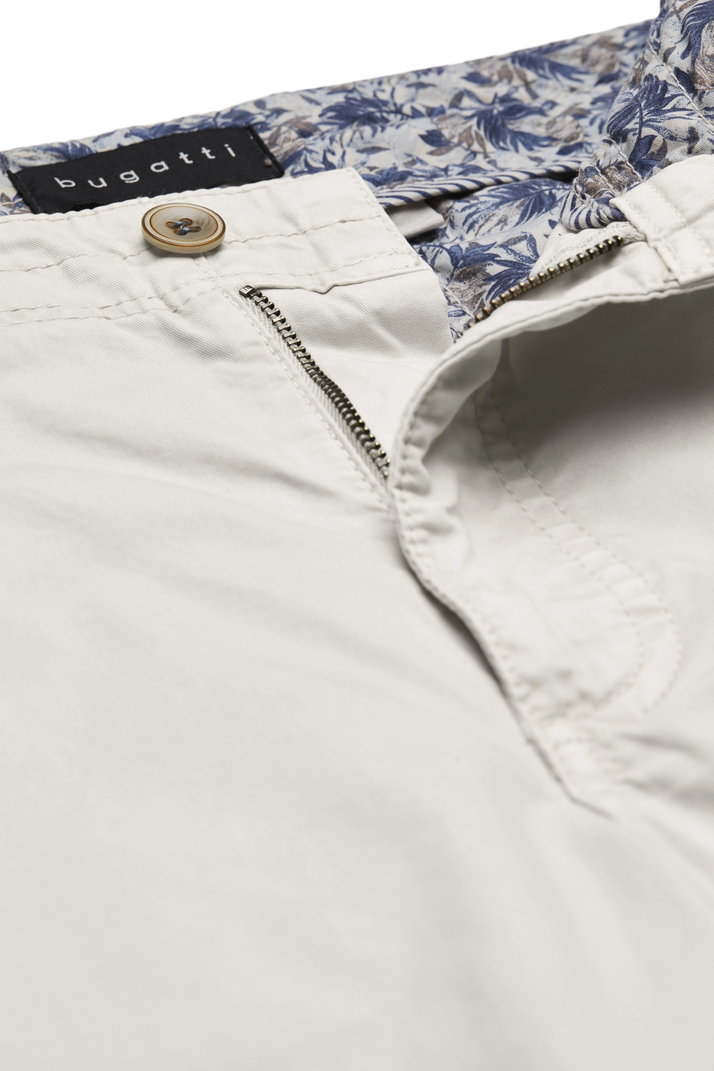 Beige bugatti broek met bloemenvoering en knoopdetail, close-up.
