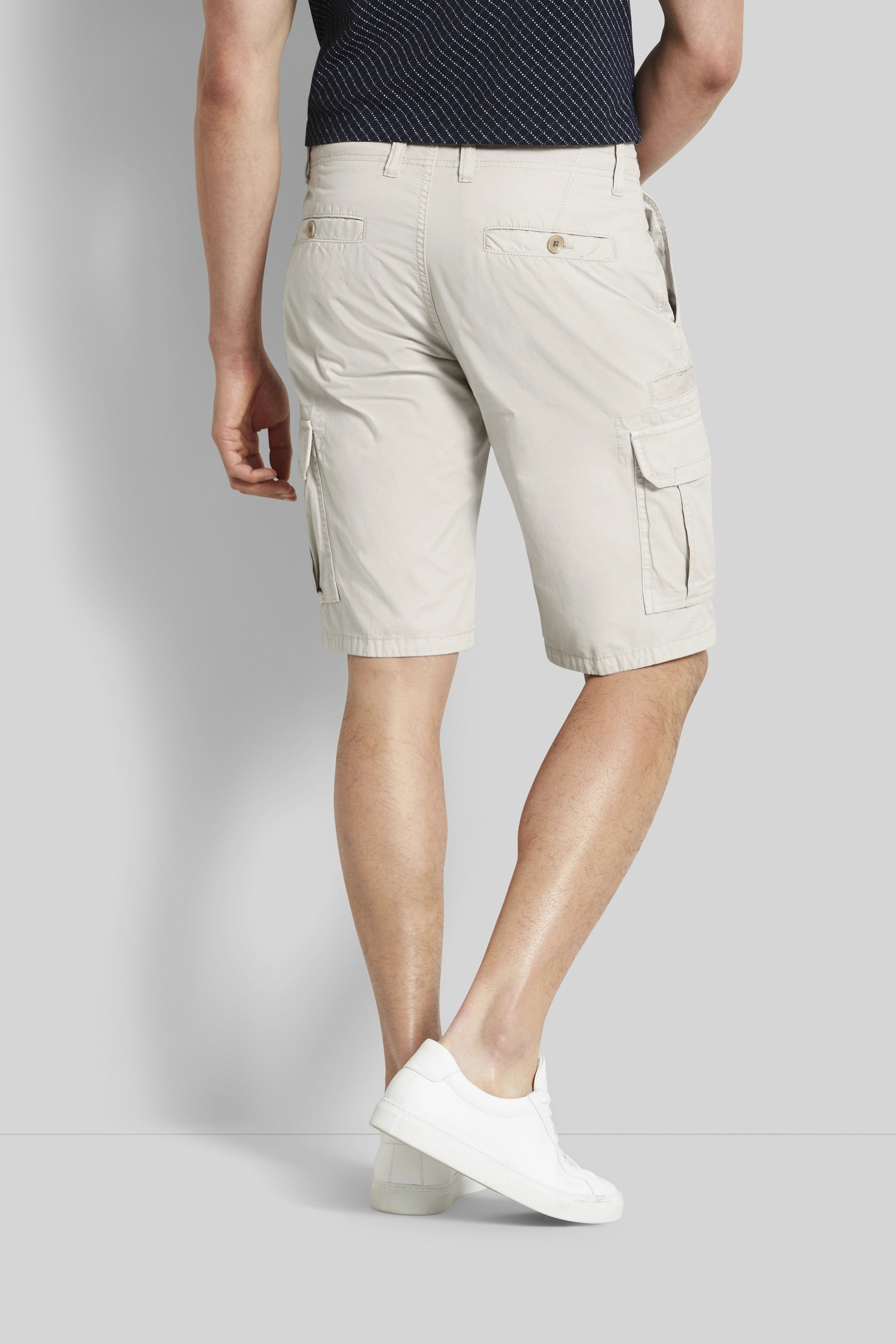 Beige cargo shorts van bugatti, casual modelbeeld, relaxte pose, gecombineerd met witte sneakers.