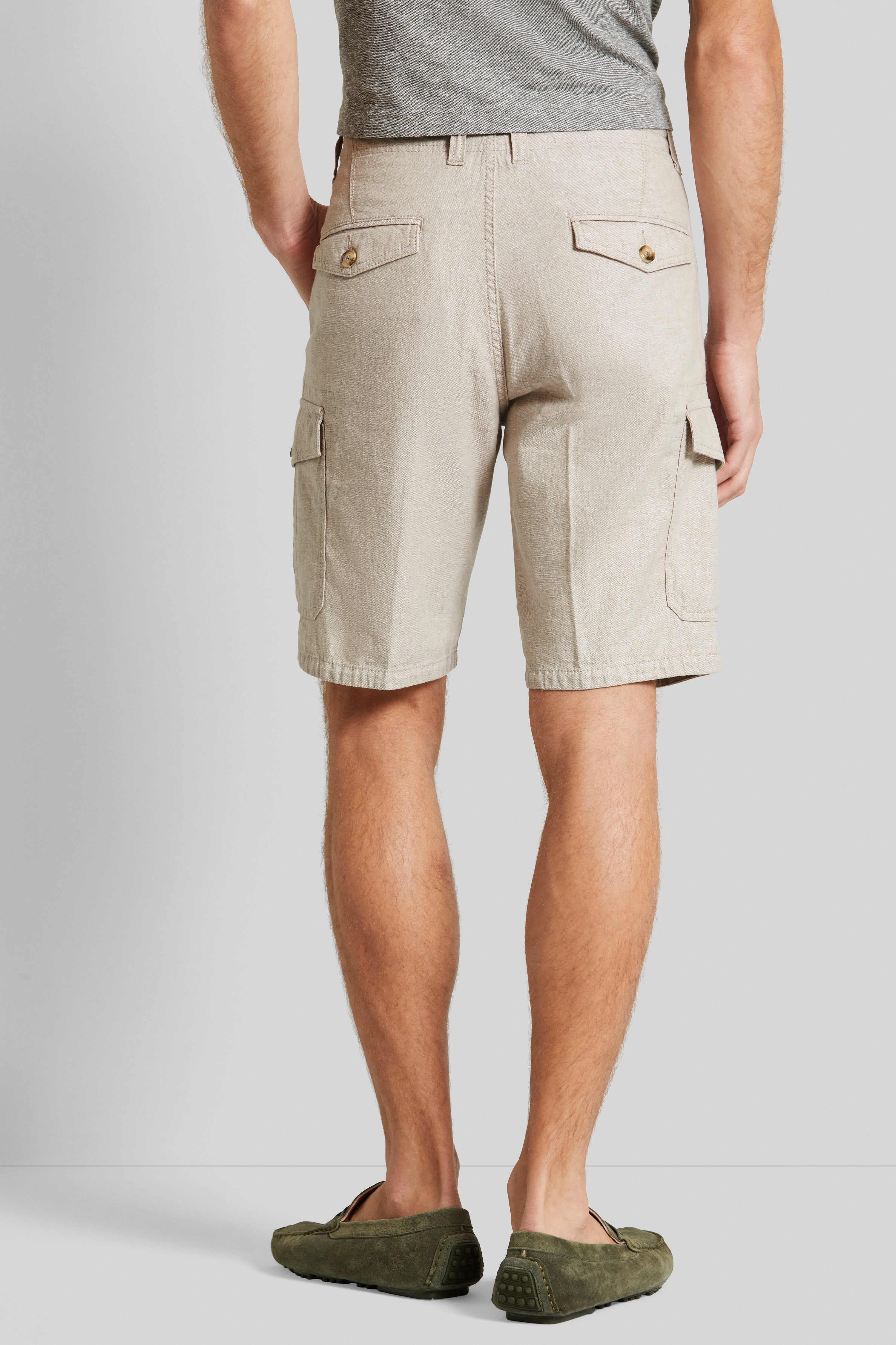 Beige Shorts mit Taschen, graues Shirt, olivgrüne Mokassins, Model von hinten stehend.