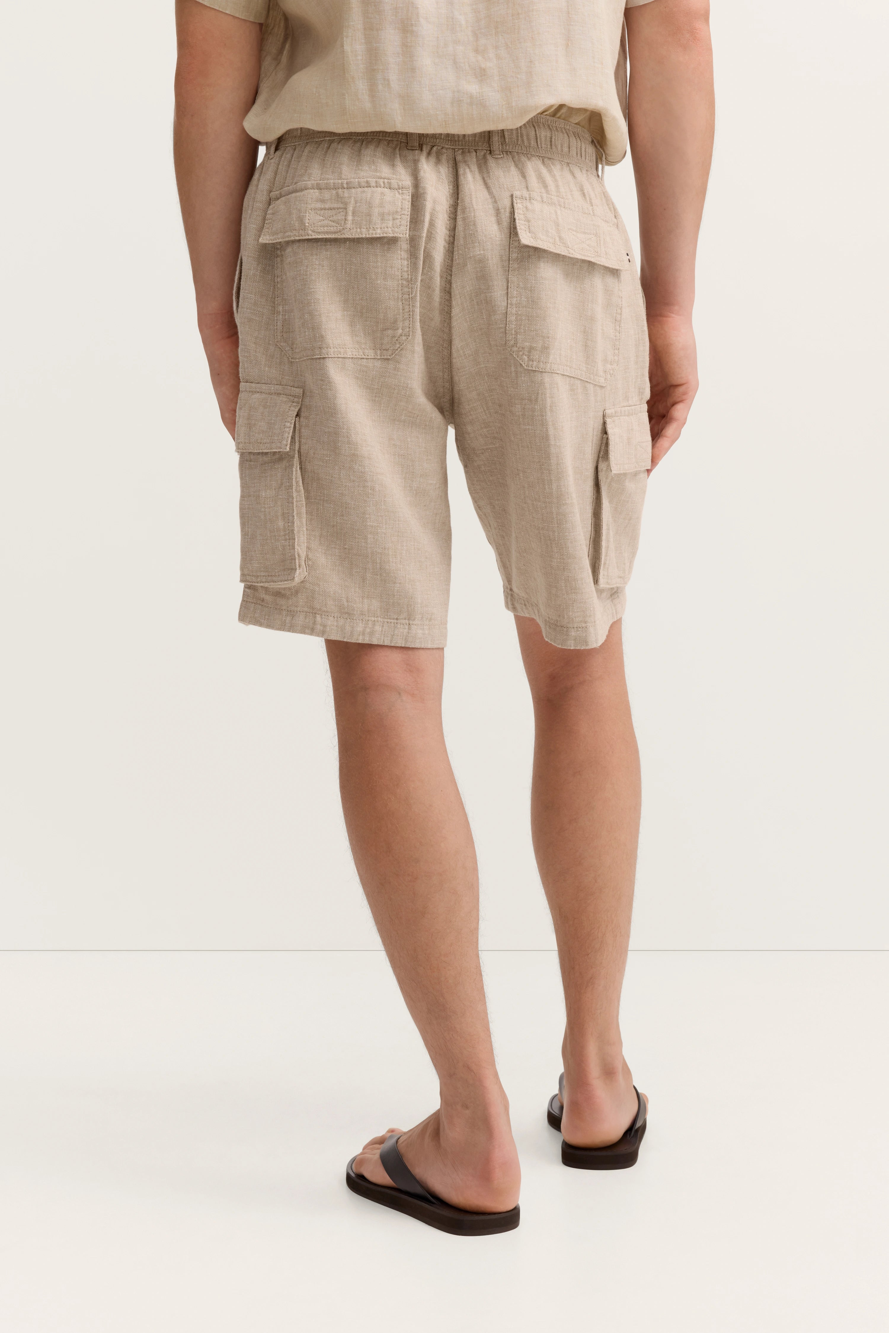 Beige Leinen-Shorts mit Taschen, legeres Modelbild von hinten, entspannte Pose, bugatti.