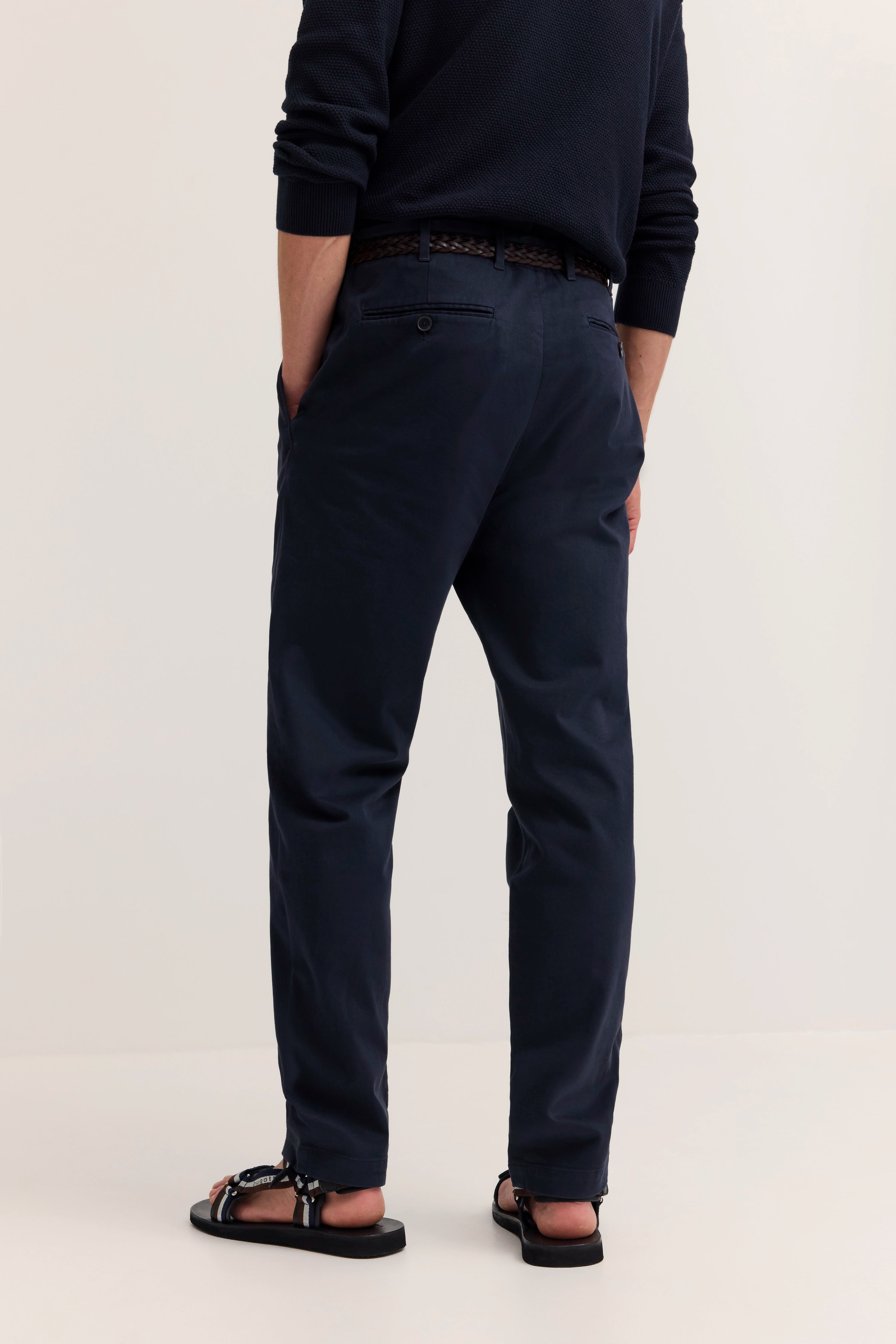 Dunkelblaues Herrenoutfit von bugatti, Model in legerer Pose, Sandalen und Chinos.