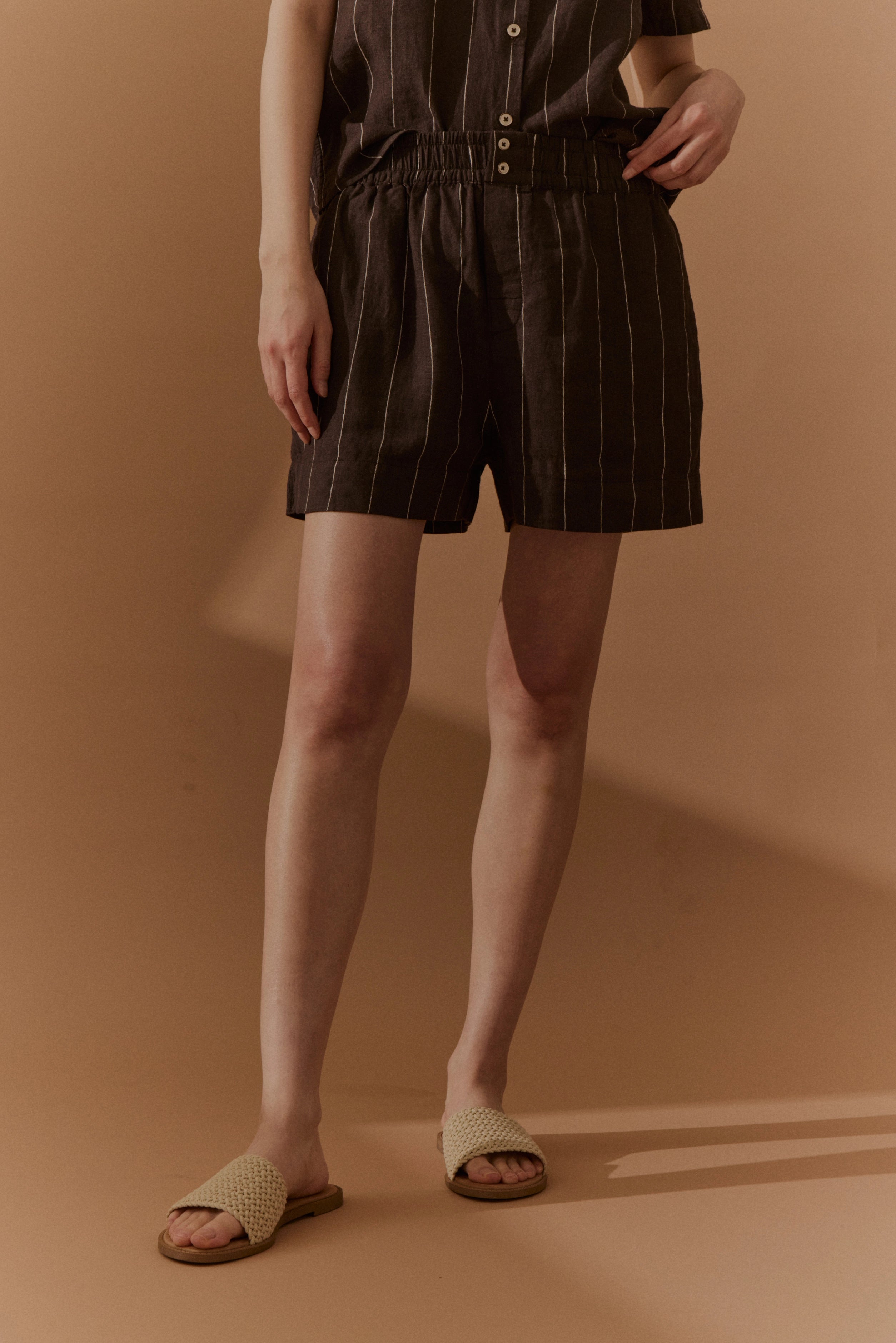 Schwarzer gestreifter Jumpsuit mit Sandalen, legeres Modelbild.